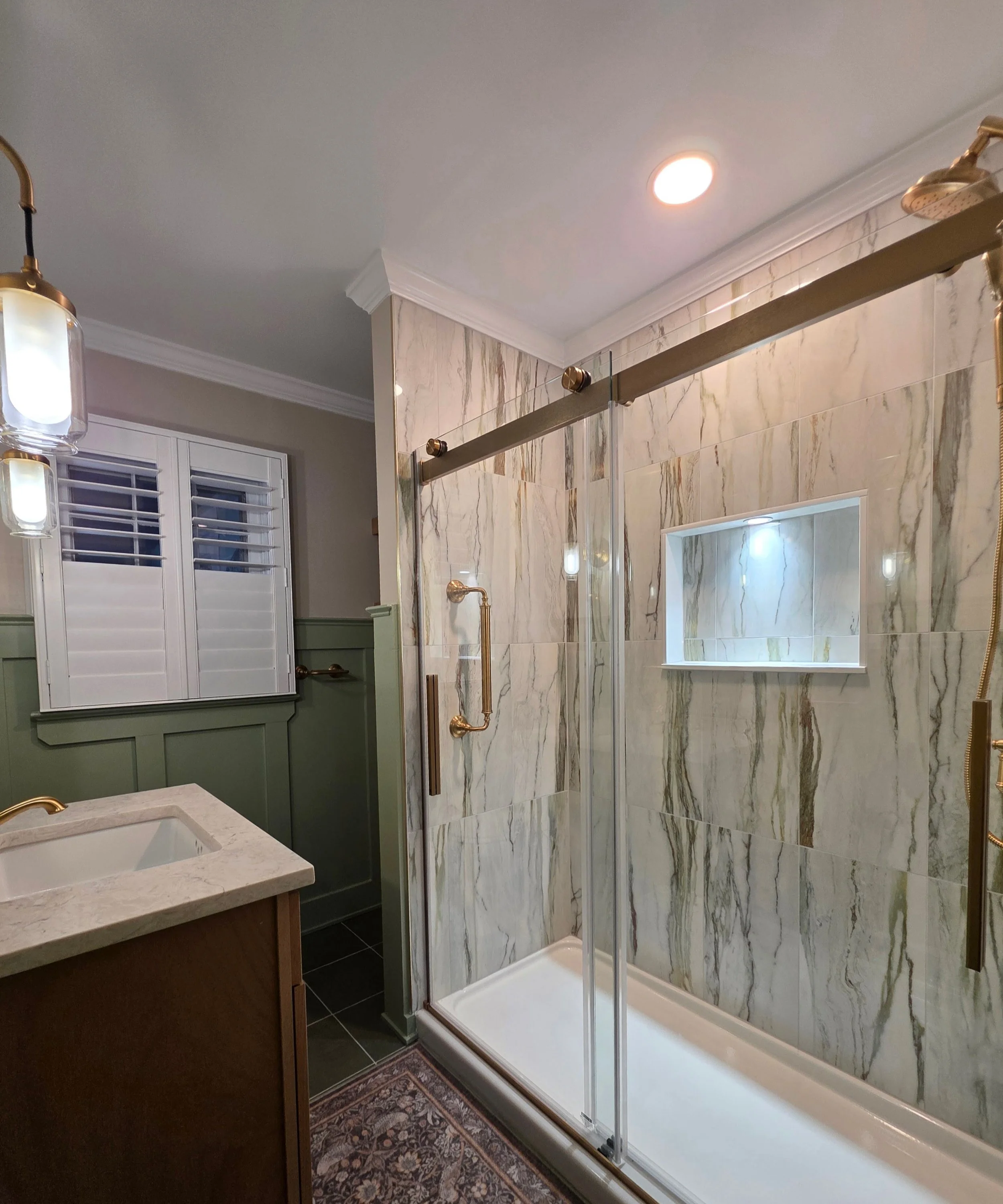 Glass shower with dramatic veined tile and lighted niche.