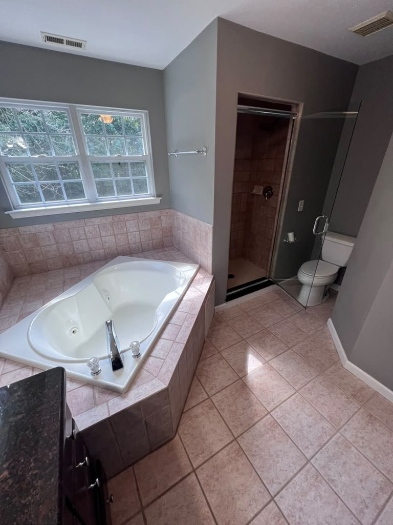 Master bathroom before renovation with built-in tub and older shower.