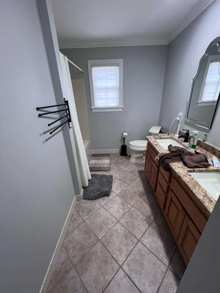 Before renovation: the original hallway bathroom with a wood vanity and diagonally laid floor tile.