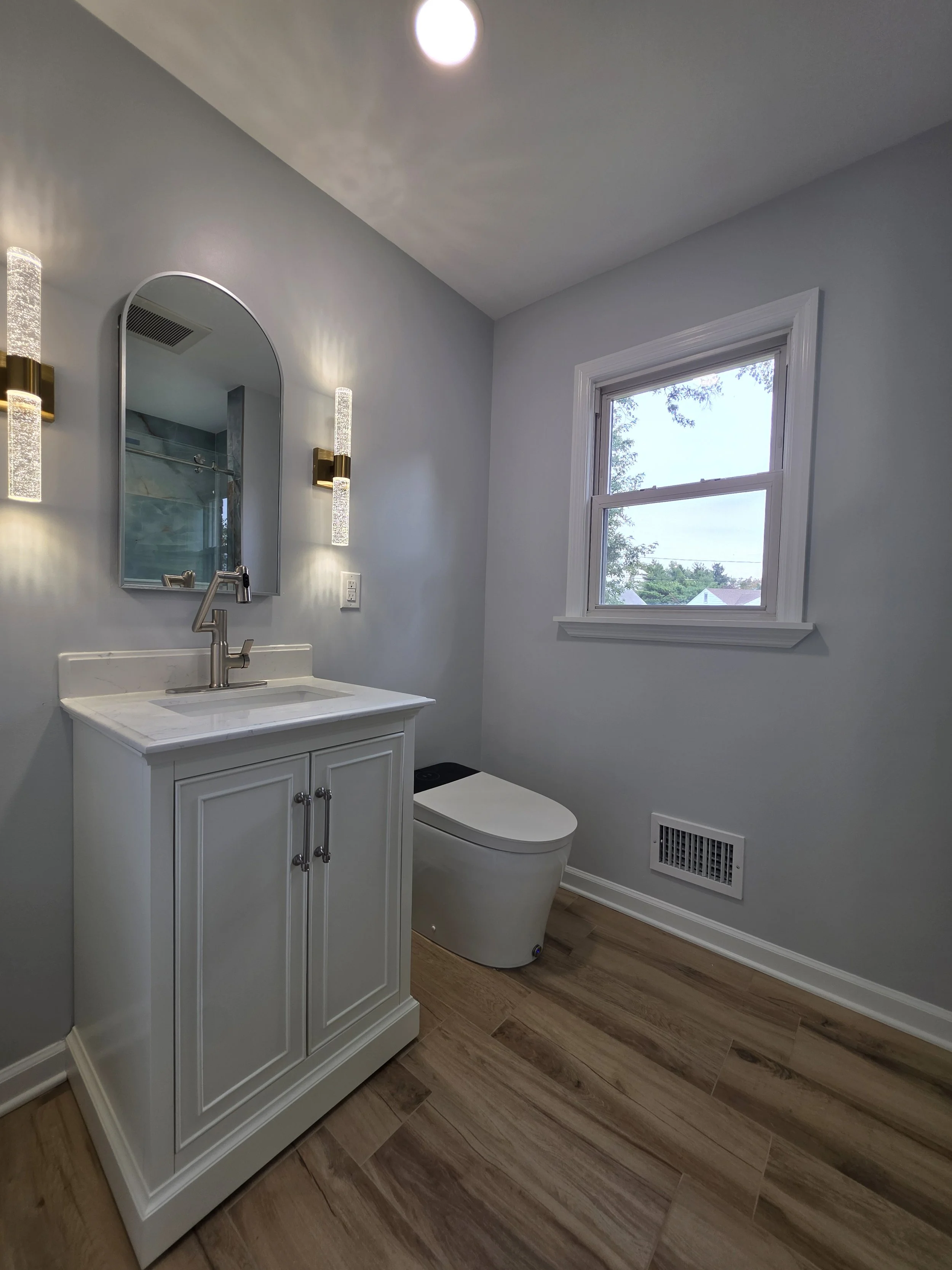 Compact vanity and toilet with wood-look flooring.