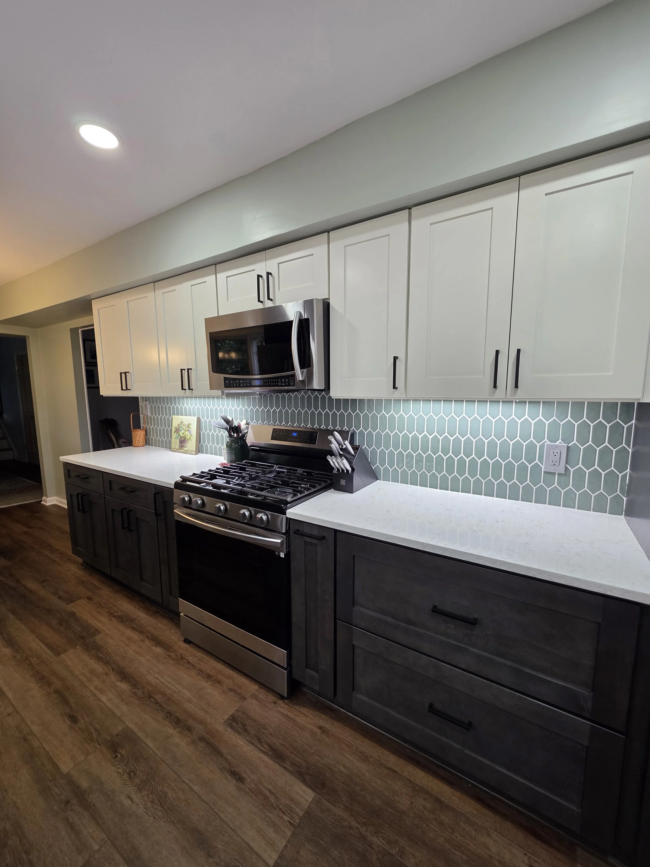 Range and microwave wall with two-tone cabinetry and light countertops.
