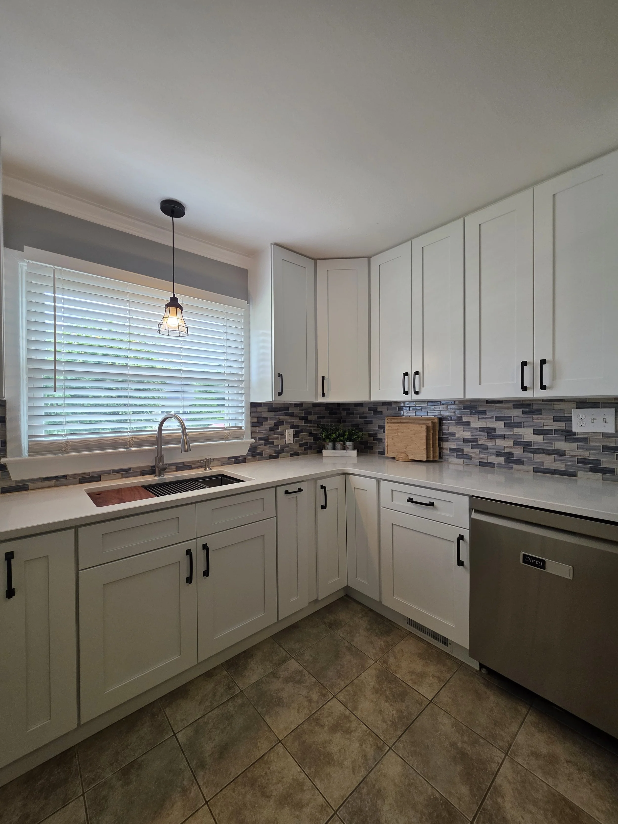 Corner sink area with light countertop and dark cabinet pulls.
