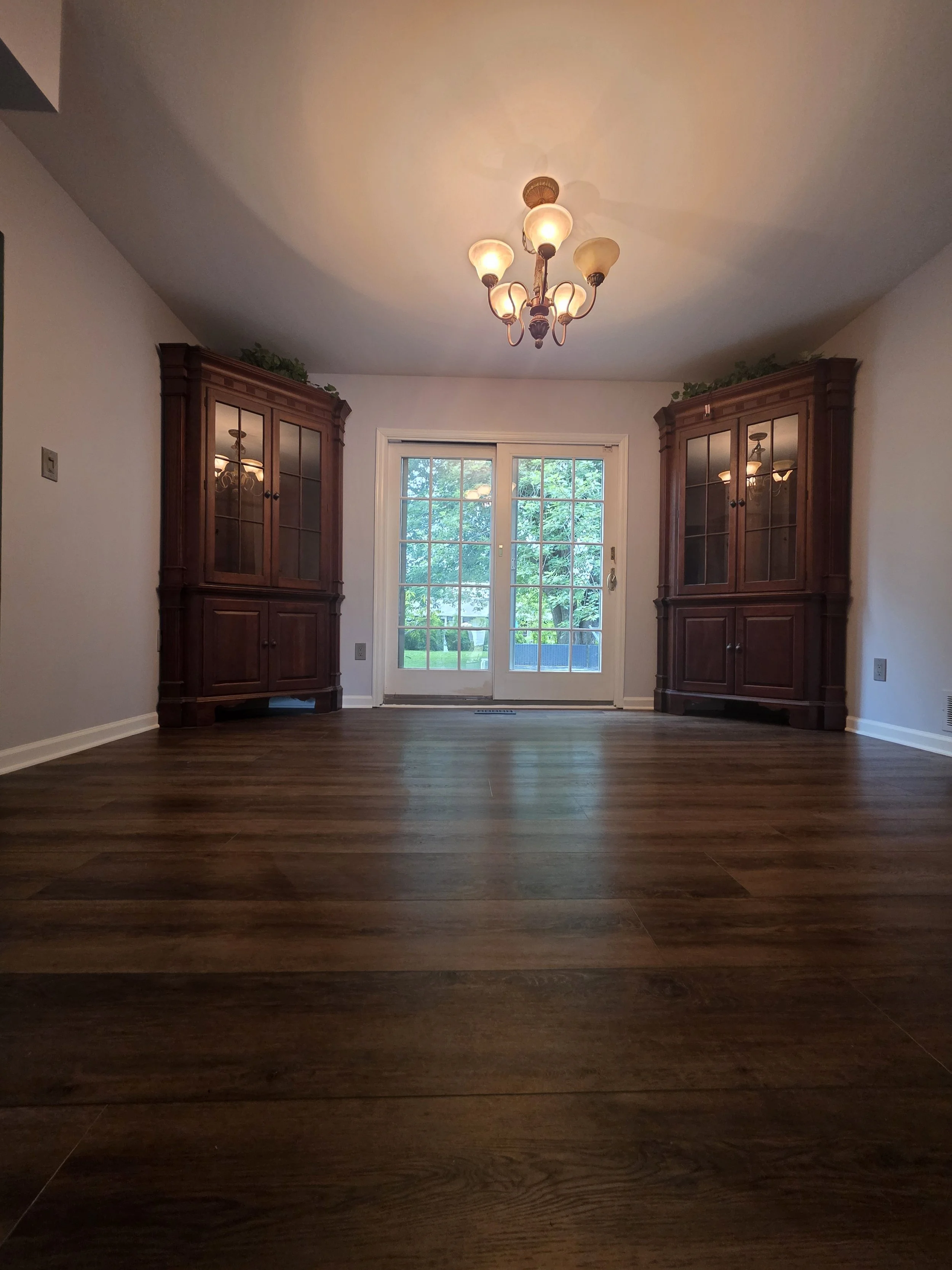 Wide view of the remodeled dining room toward the glass doors and chandelier.
