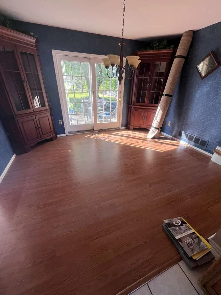 Before renovation: the dining room with older flooring and dark wall paint.