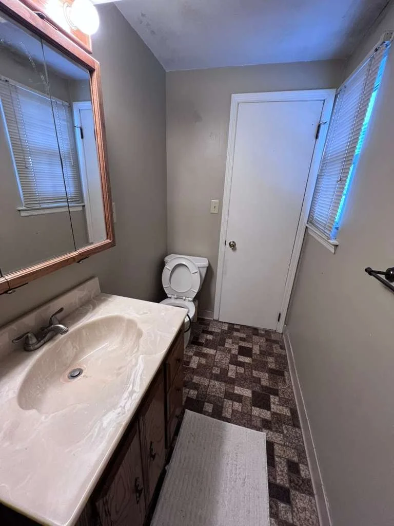 Before renovation: the original basement bathroom vanity and toilet with patterned floor tile.