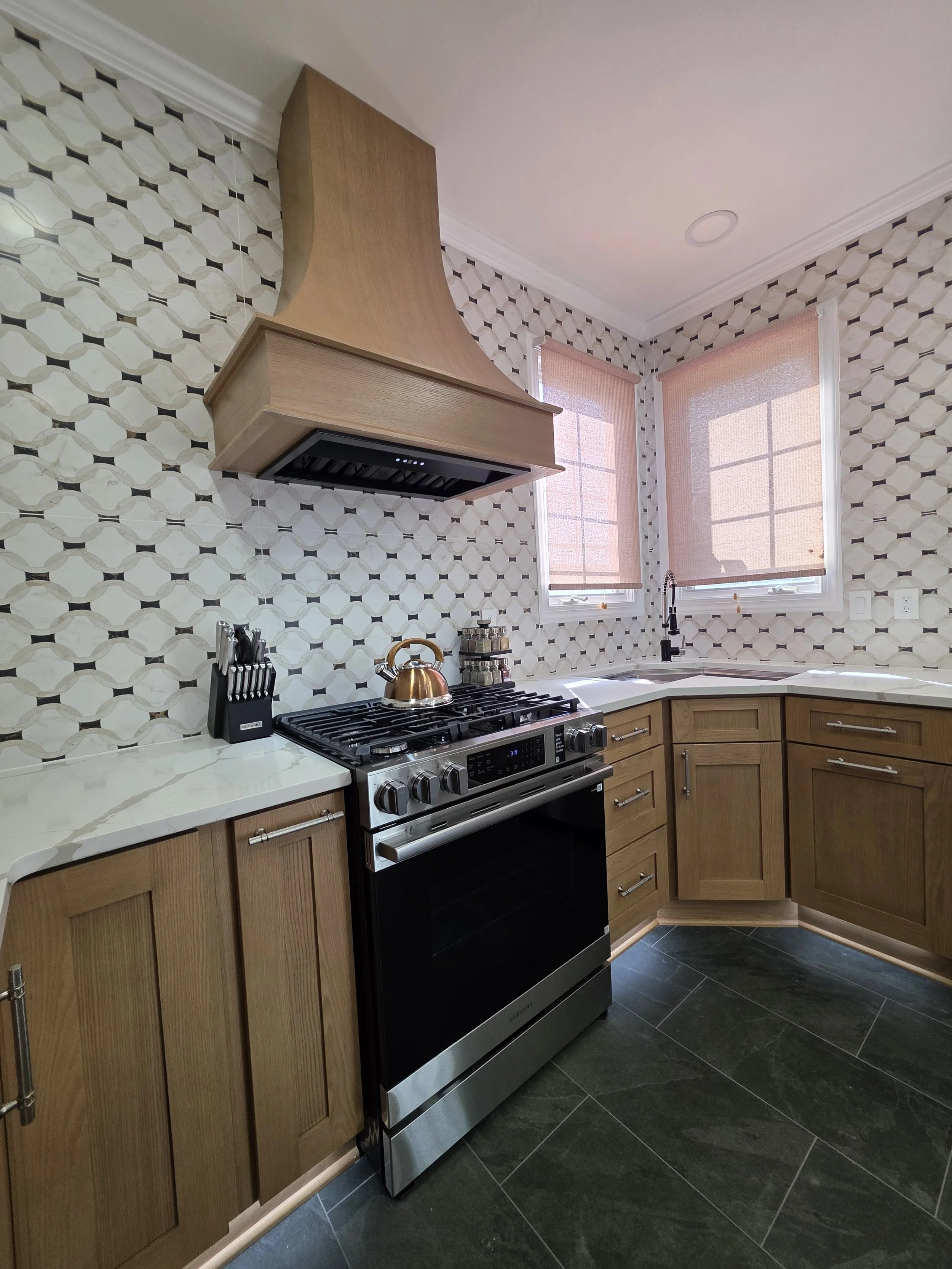 Kitchen corner with sink, range and patterned tile walls.
