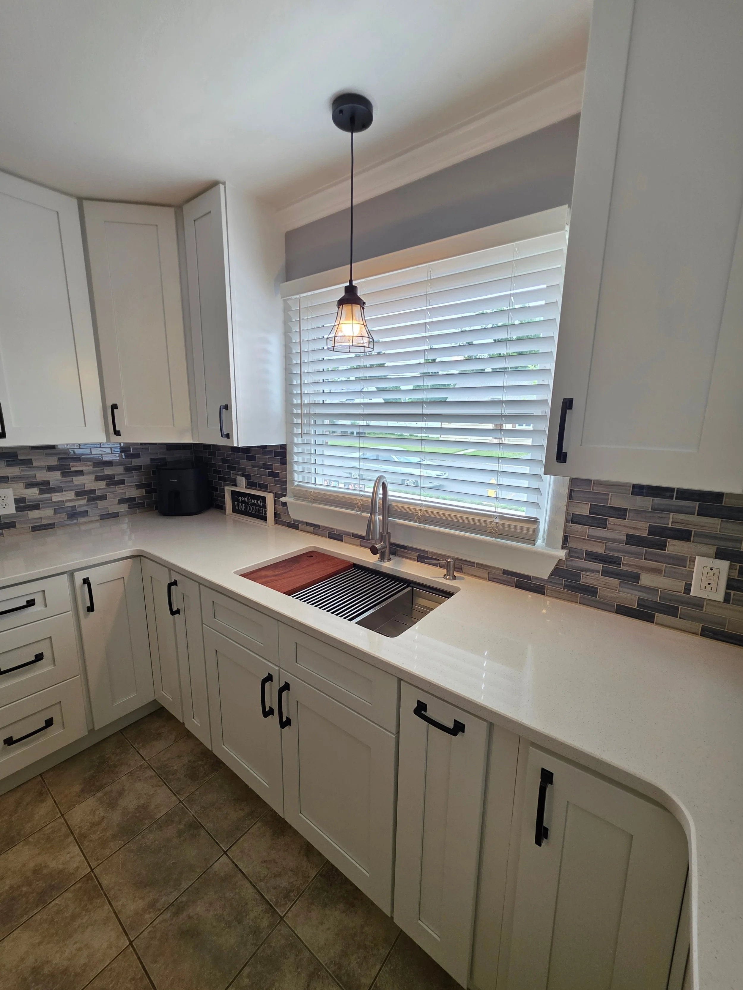 Kitchen sink below window and patterned backsplash.