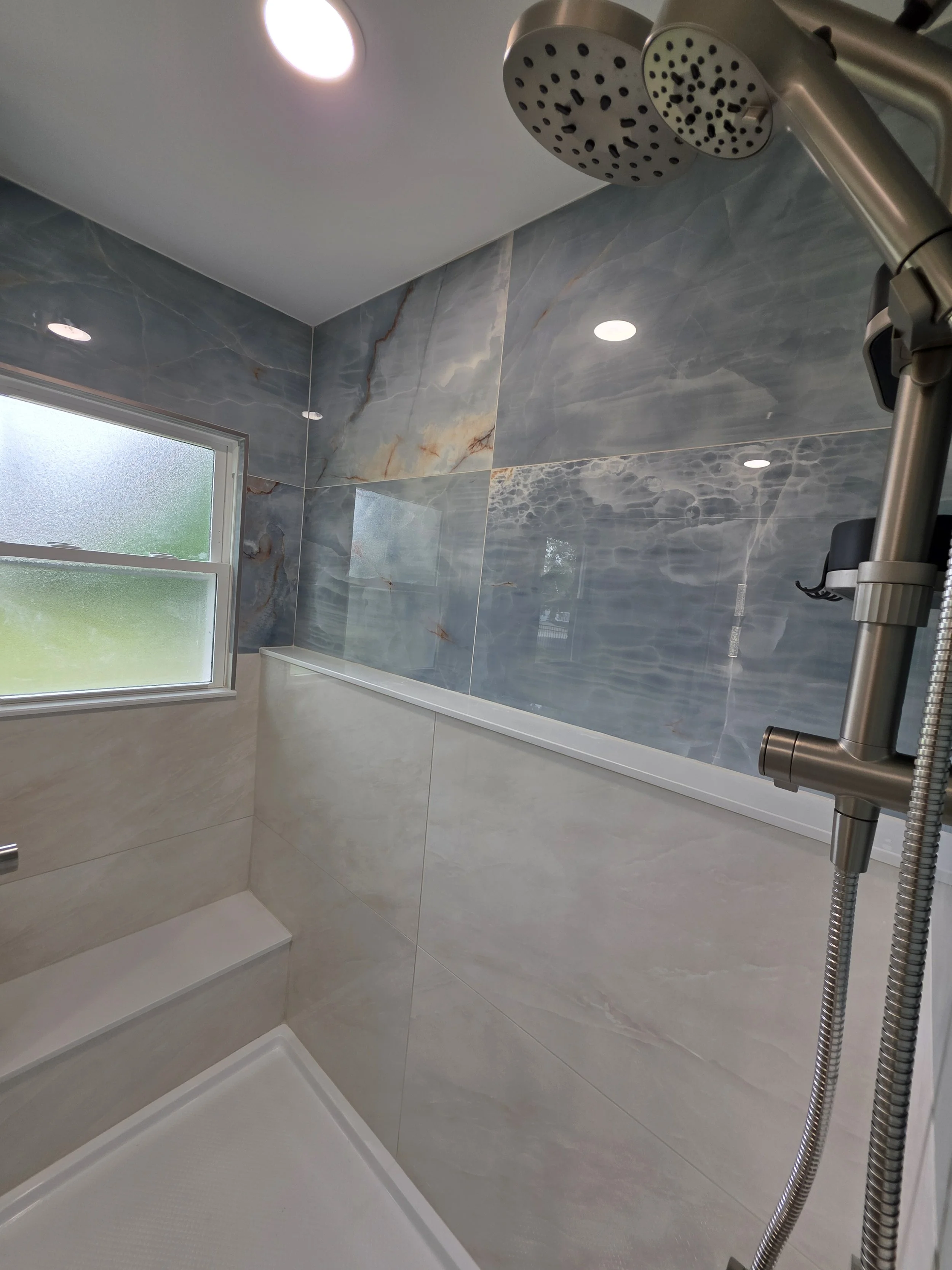 Blue upper shower tile, beige lower tile and rain shower.