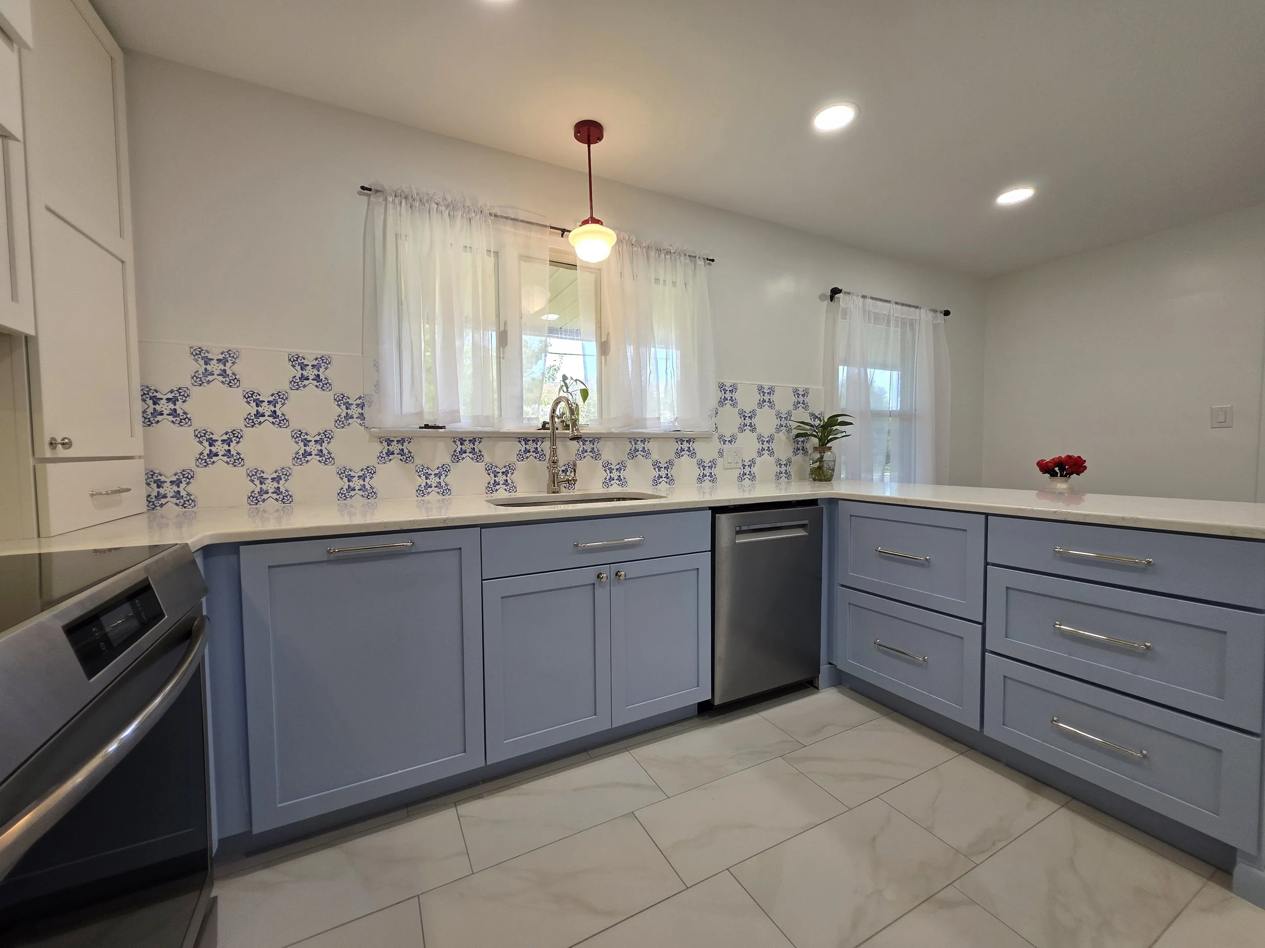 Sink below the window with blue base cabinets.