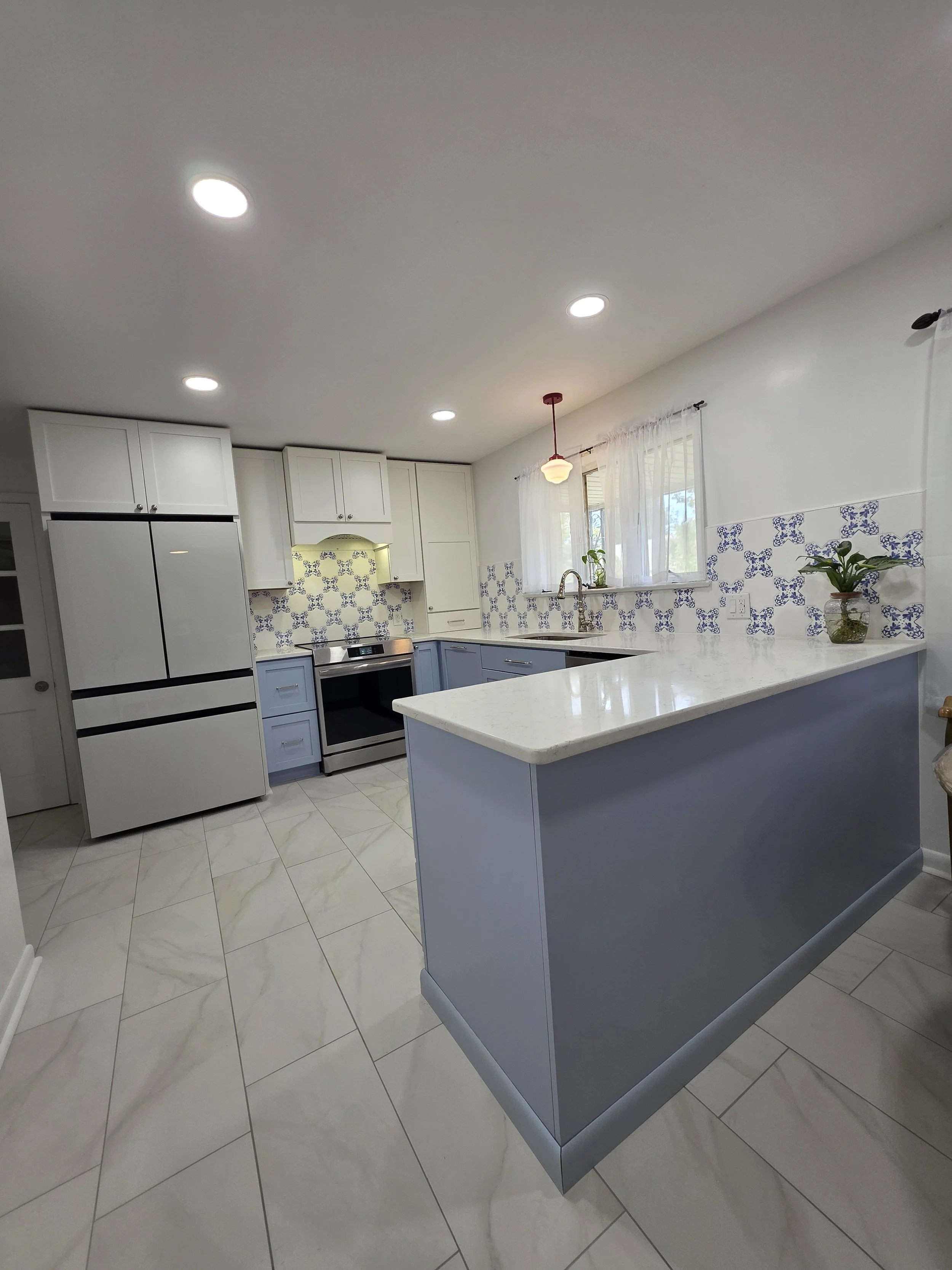 Bevin and TJ’s kitchen with blue lower cabinets, white uppers and peninsula.