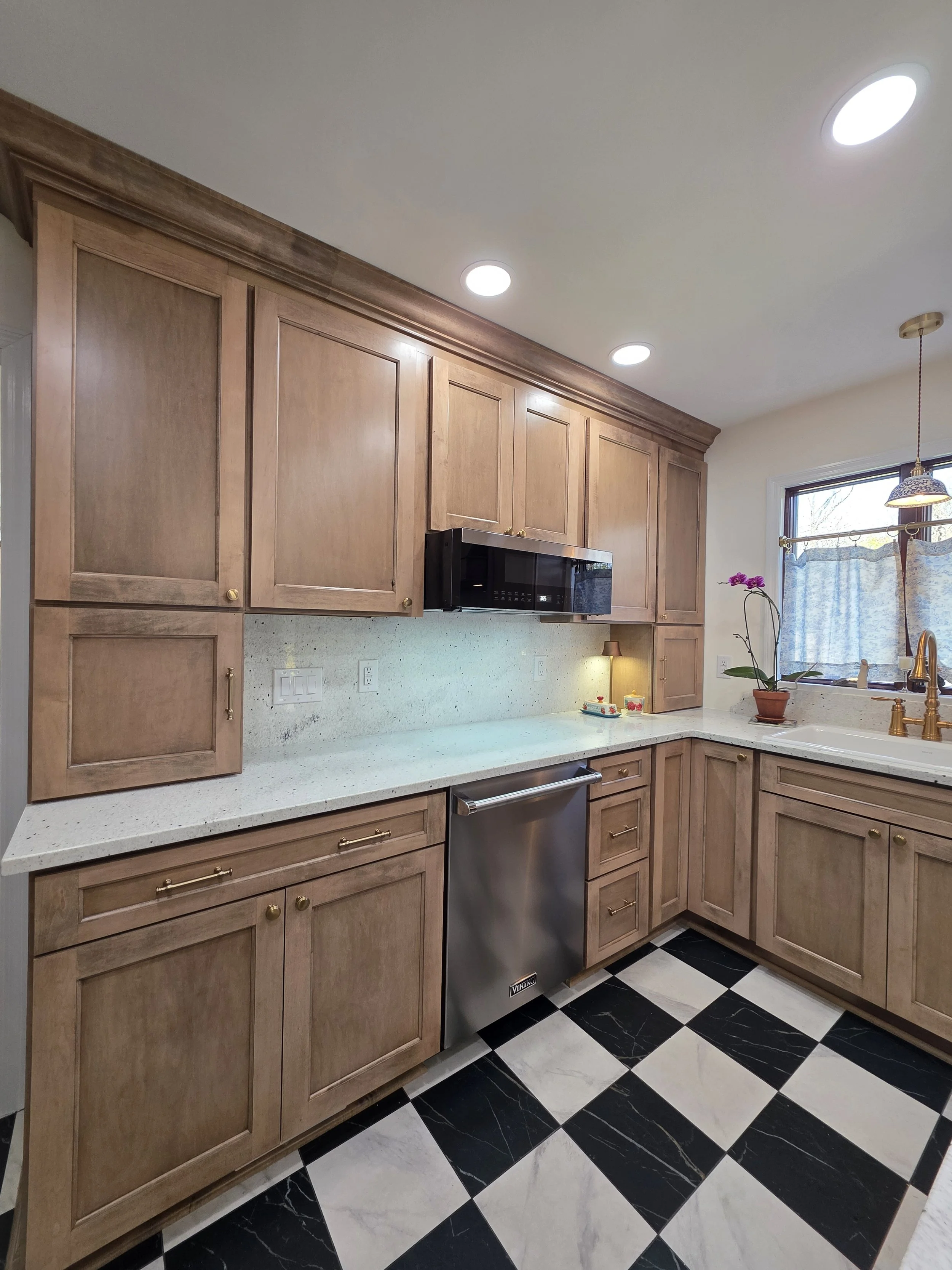 Wood cabinets and microwave above the countertop, with dishwasher beside the sink.