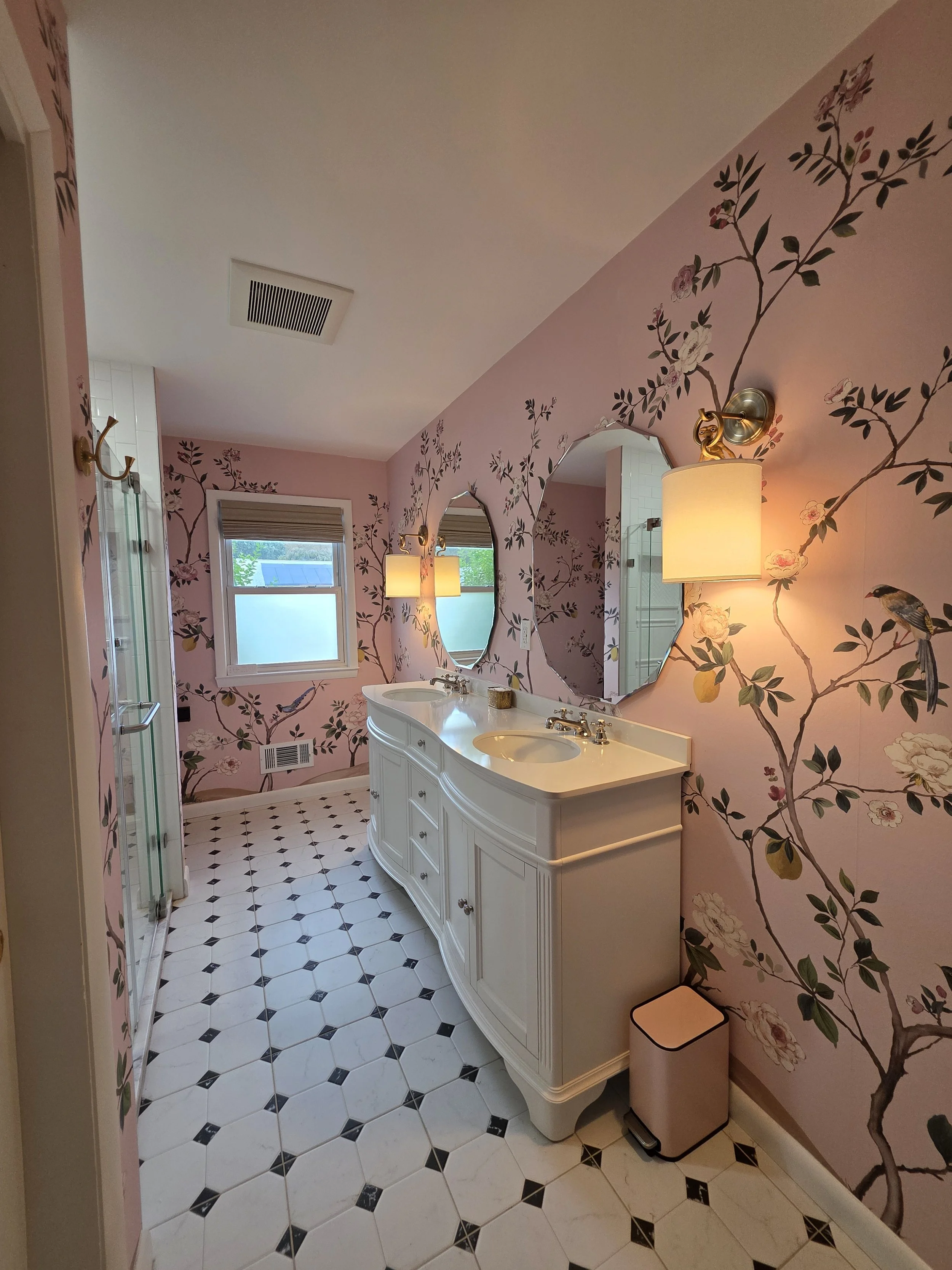 Pink botanical wallpaper and patterned floor beside vanity.
