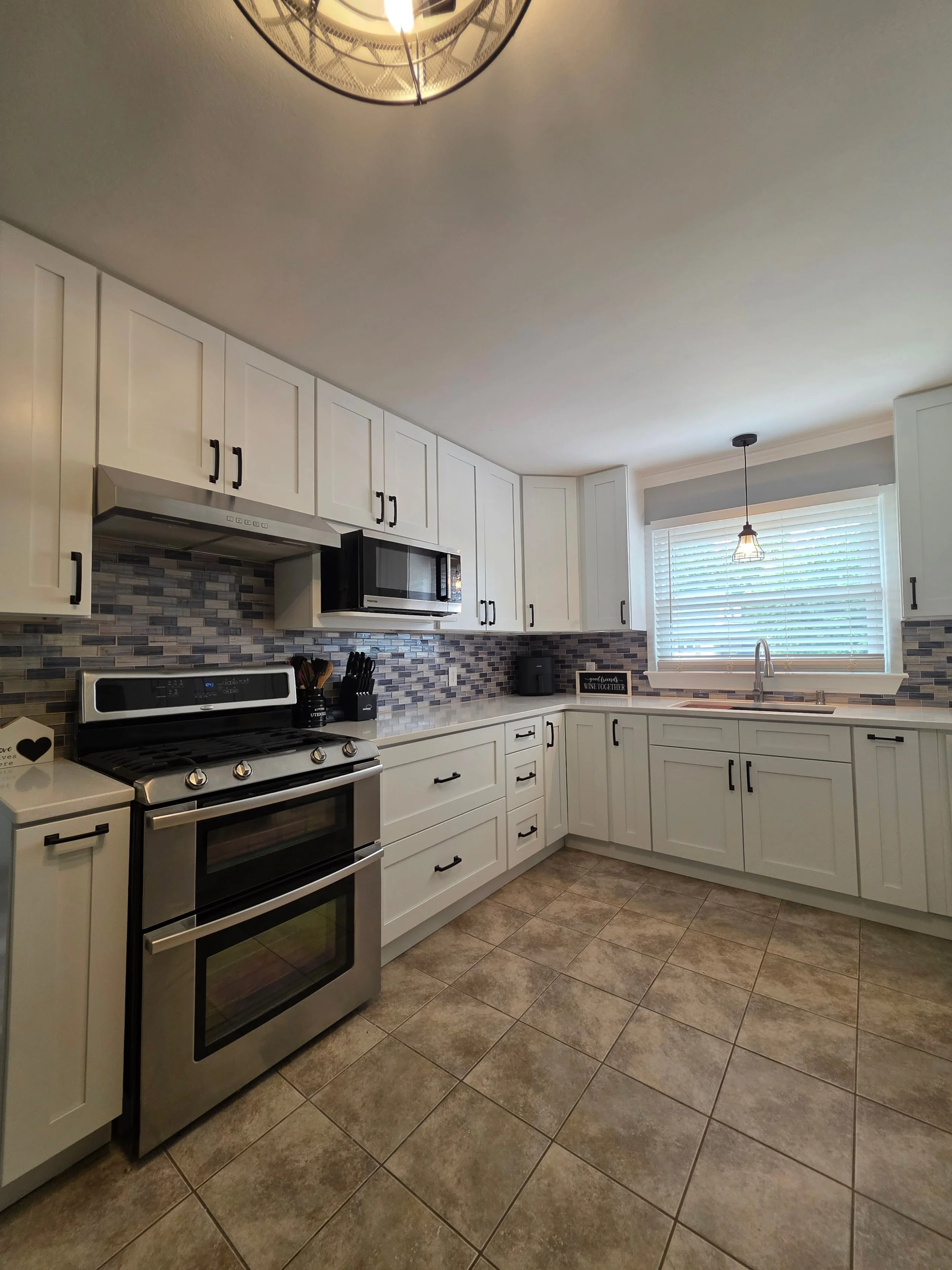 Kristen and Eddie’s completed kitchen with white cabinets and tile backsplash.