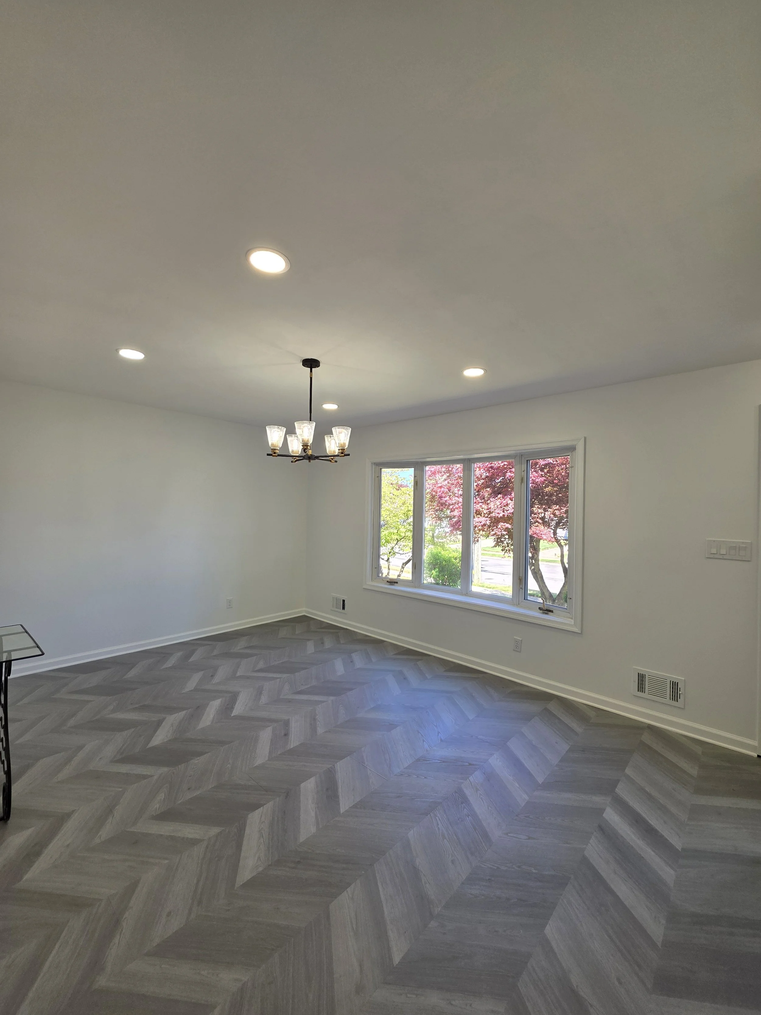 Refreshed dining room with a hanging light, pale walls and herringbone-pattern floor.