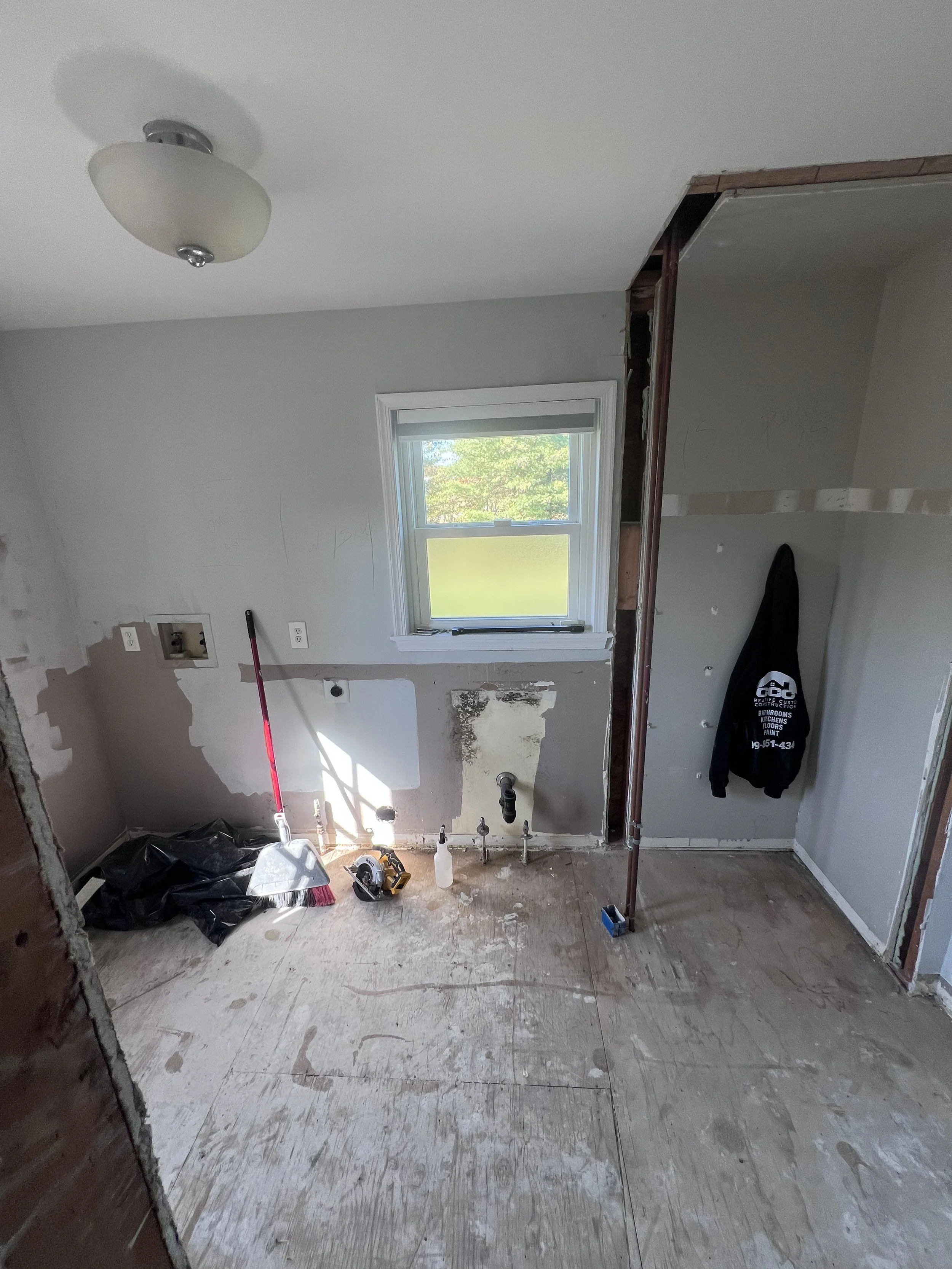 Before renovation: the laundry room with stripped walls and flooring before new cabinets and appliances.