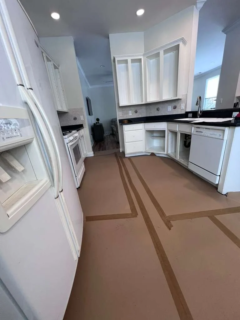 Before renovation: the original white kitchen cabinets with protective floor covering.