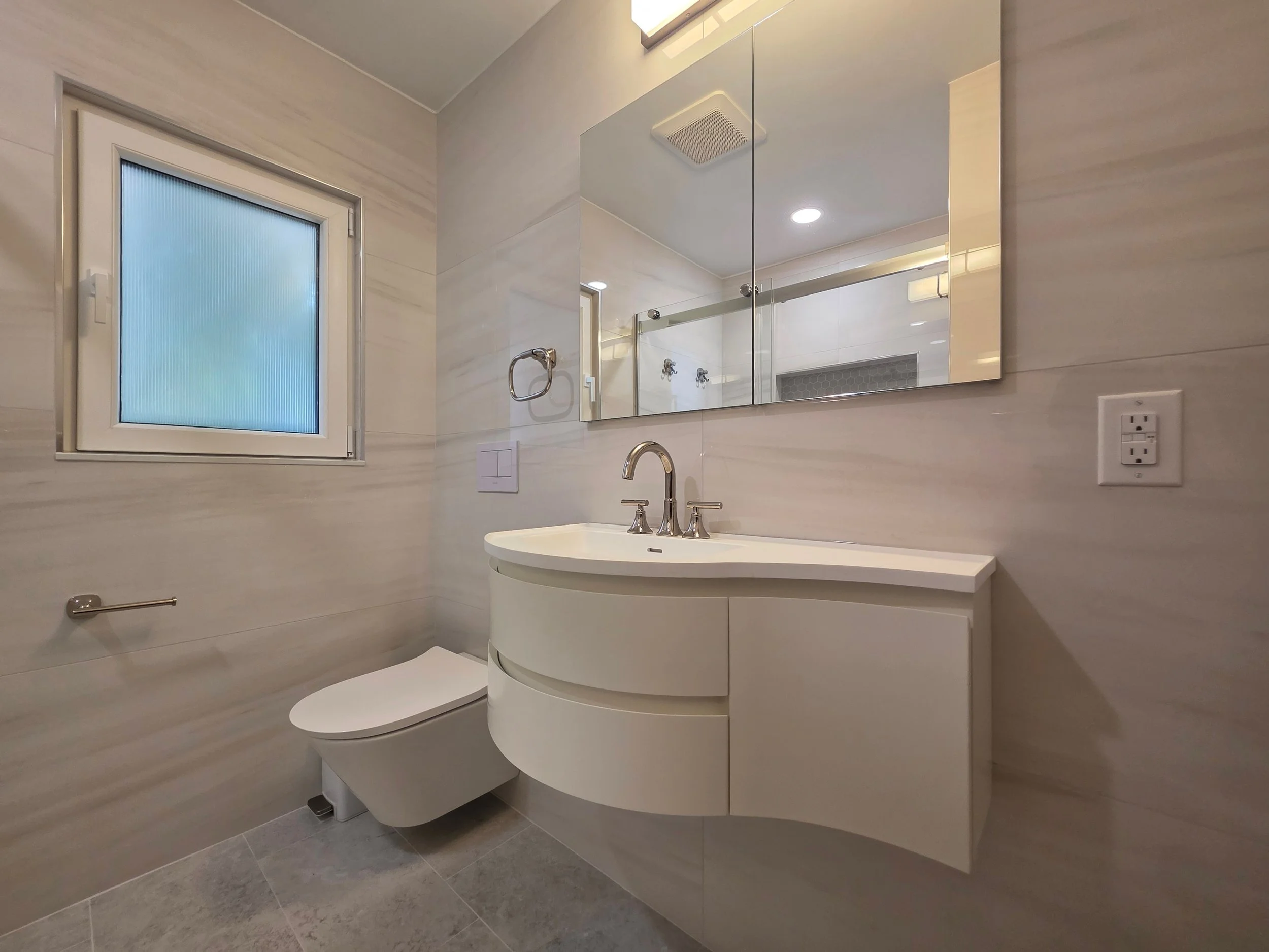 Floating vanity and wall-hung toilet beneath mirrored cabinet.