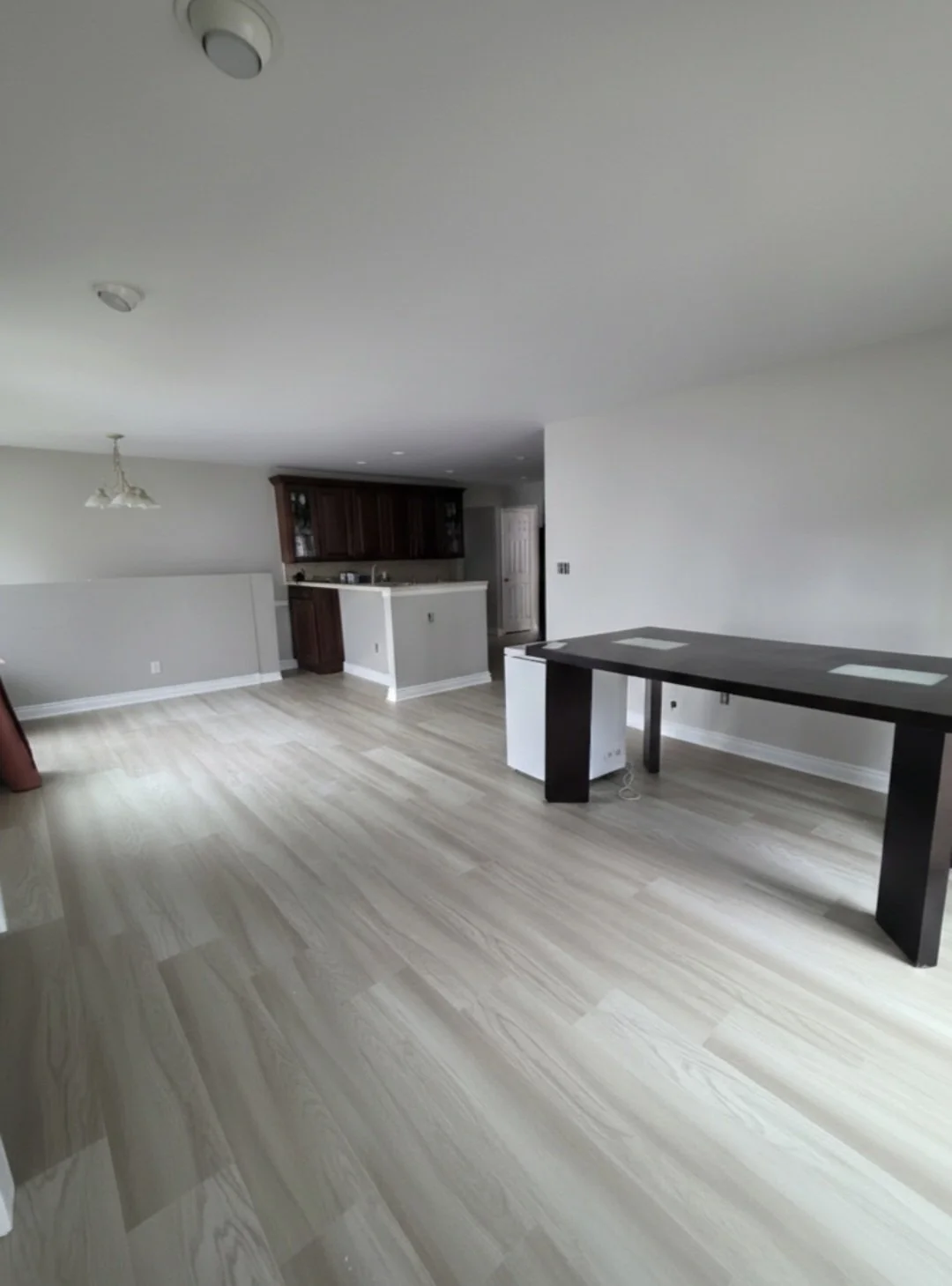 Continuous light vinyl flooring through the open living area toward the kitchen.