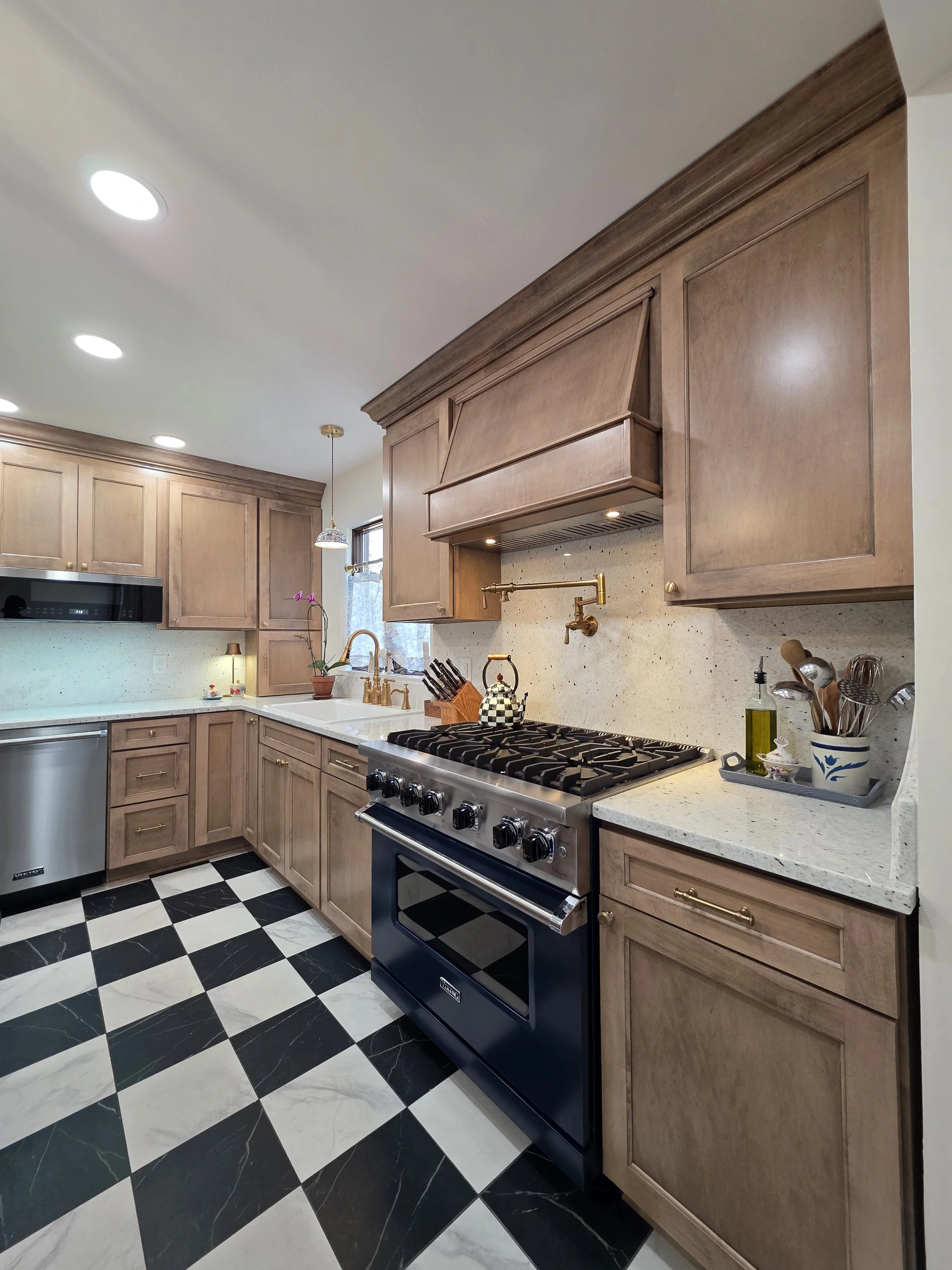 Angled view of the range wall with wood cabinets and checkerboard flooring.