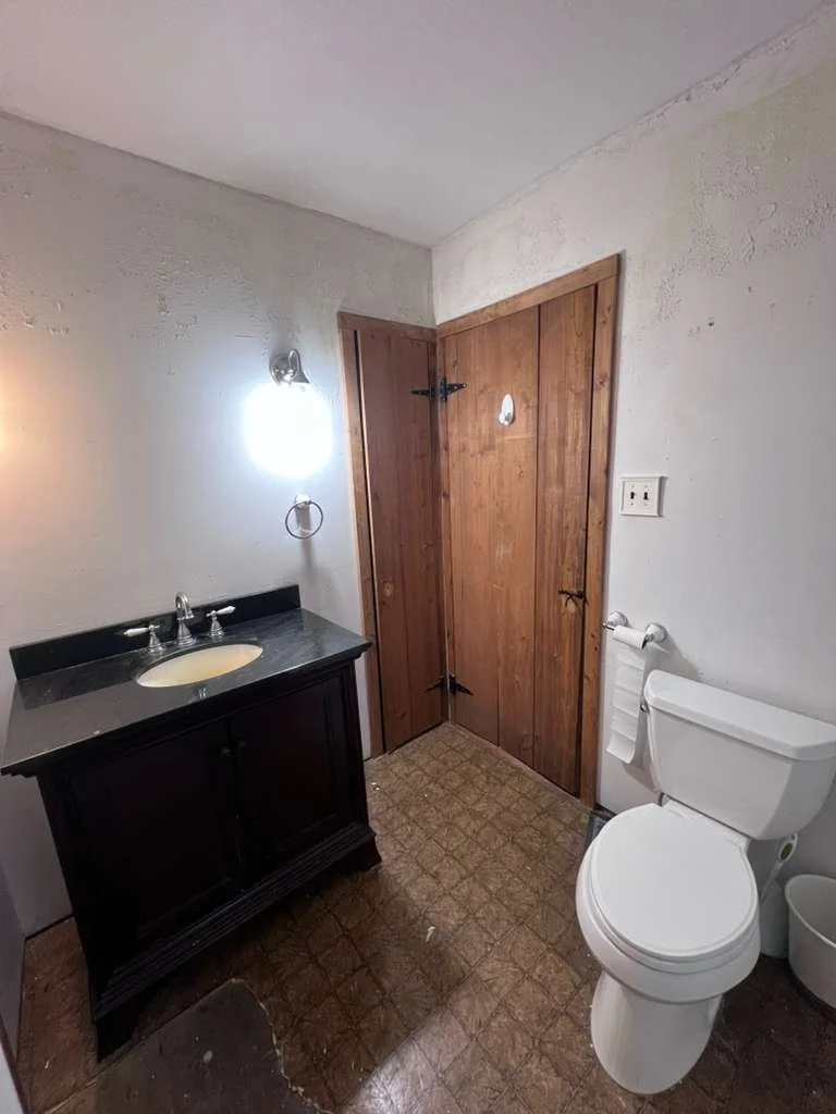 Before renovation: the original vanity, toilet and older bathroom flooring.
