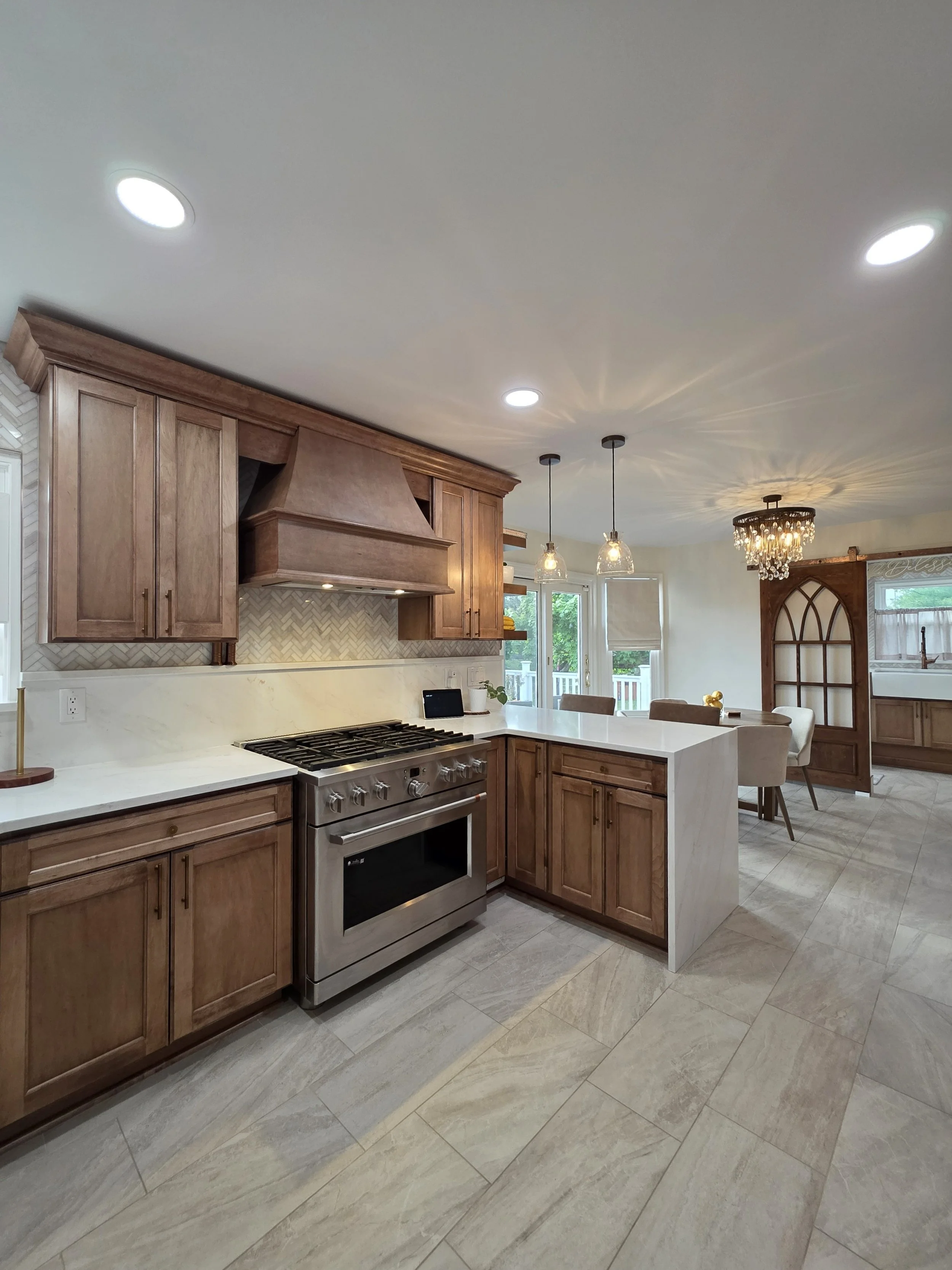 Vinny and Francesca’s remodeled kitchen with rich wood cabinetry, a matching range hood and peninsula seating.