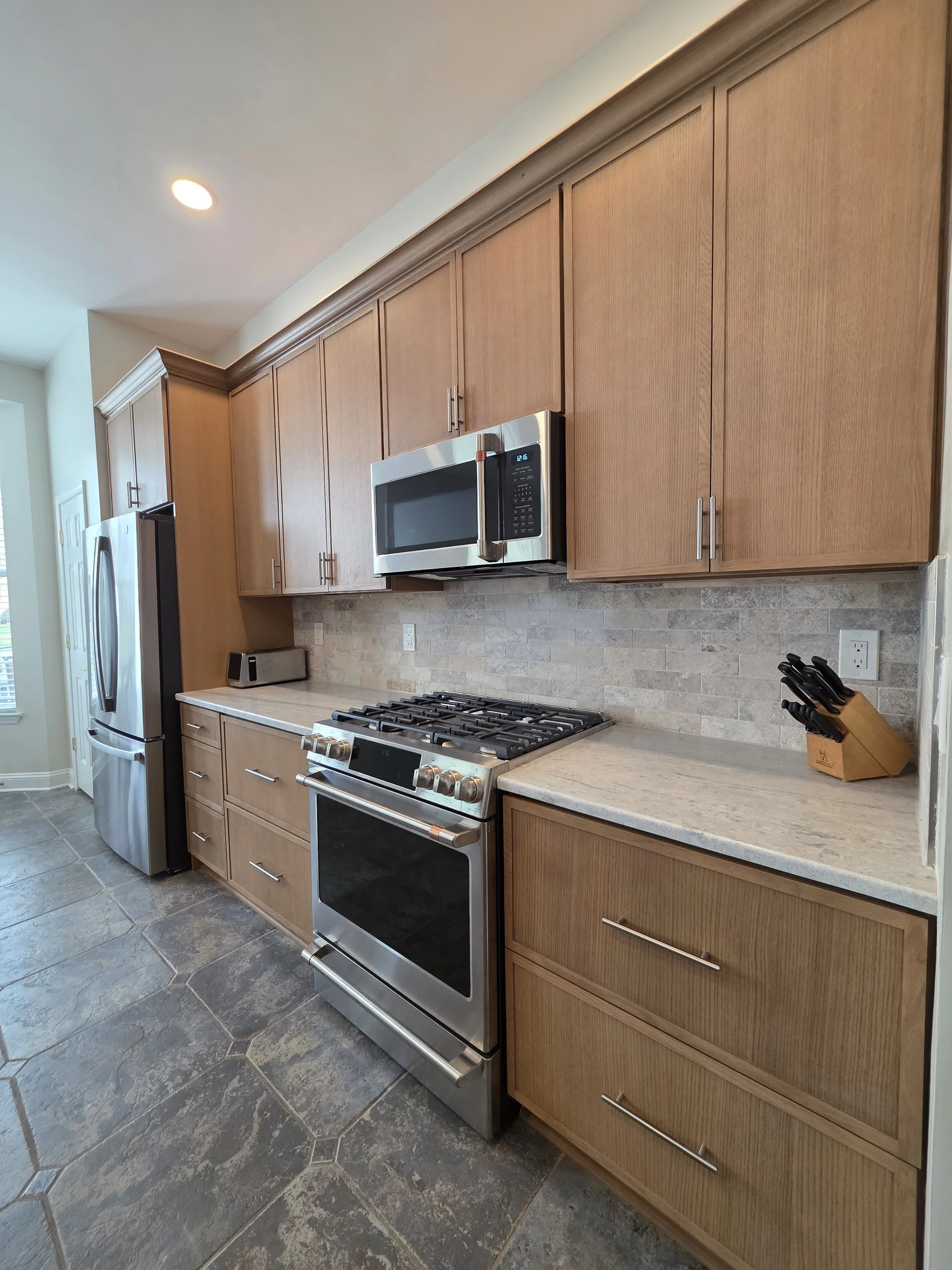 Angled view along the range wall highlighting cabinet doors, drawers and crown trim.