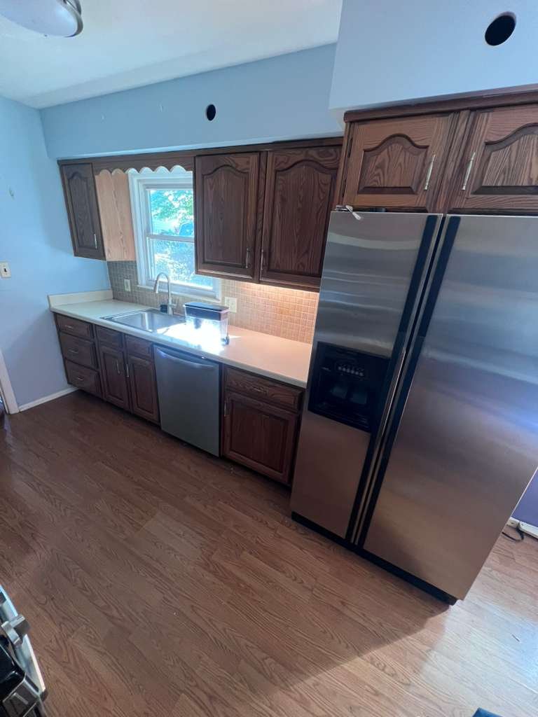 Before renovation: original sink and refrigerator wall with wood cabinets.