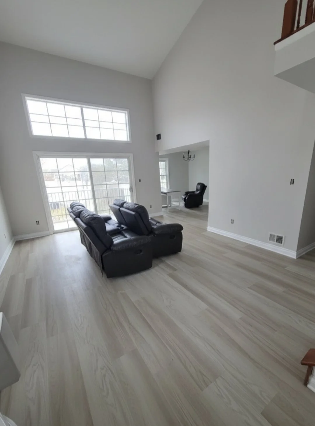 Wide view of the living area showing new light flooring beneath the high ceiling.