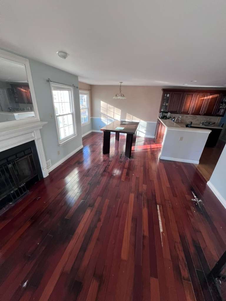 Before renovation: the original reddish wood floor through the living area and kitchen.