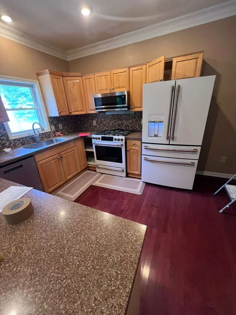 Before the kitchen update: wood-tone cabinets, dark countertops, and the existing range and refrigerator.