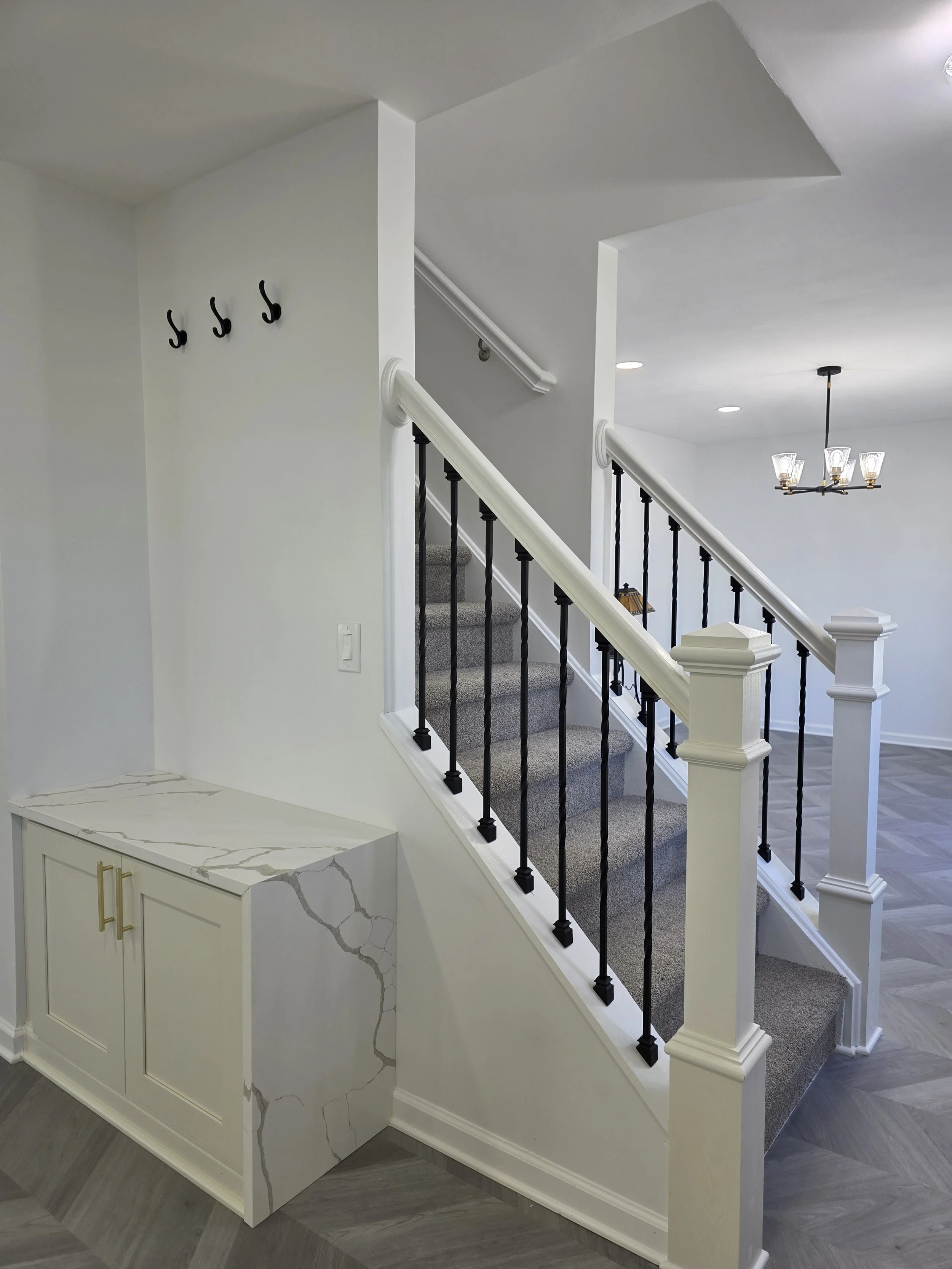Entry bench and hooks beside the staircase with contrasting dark balusters.