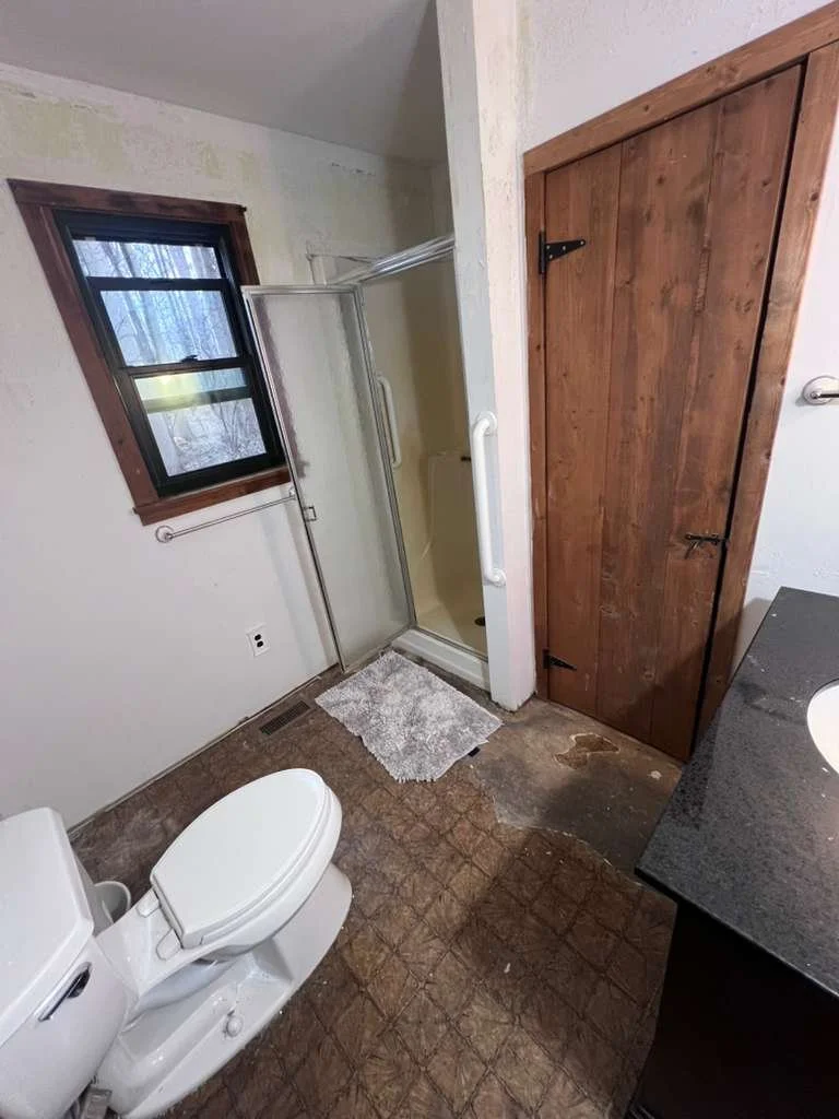 Before renovation: the original shower enclosure, window and wood bathroom door.