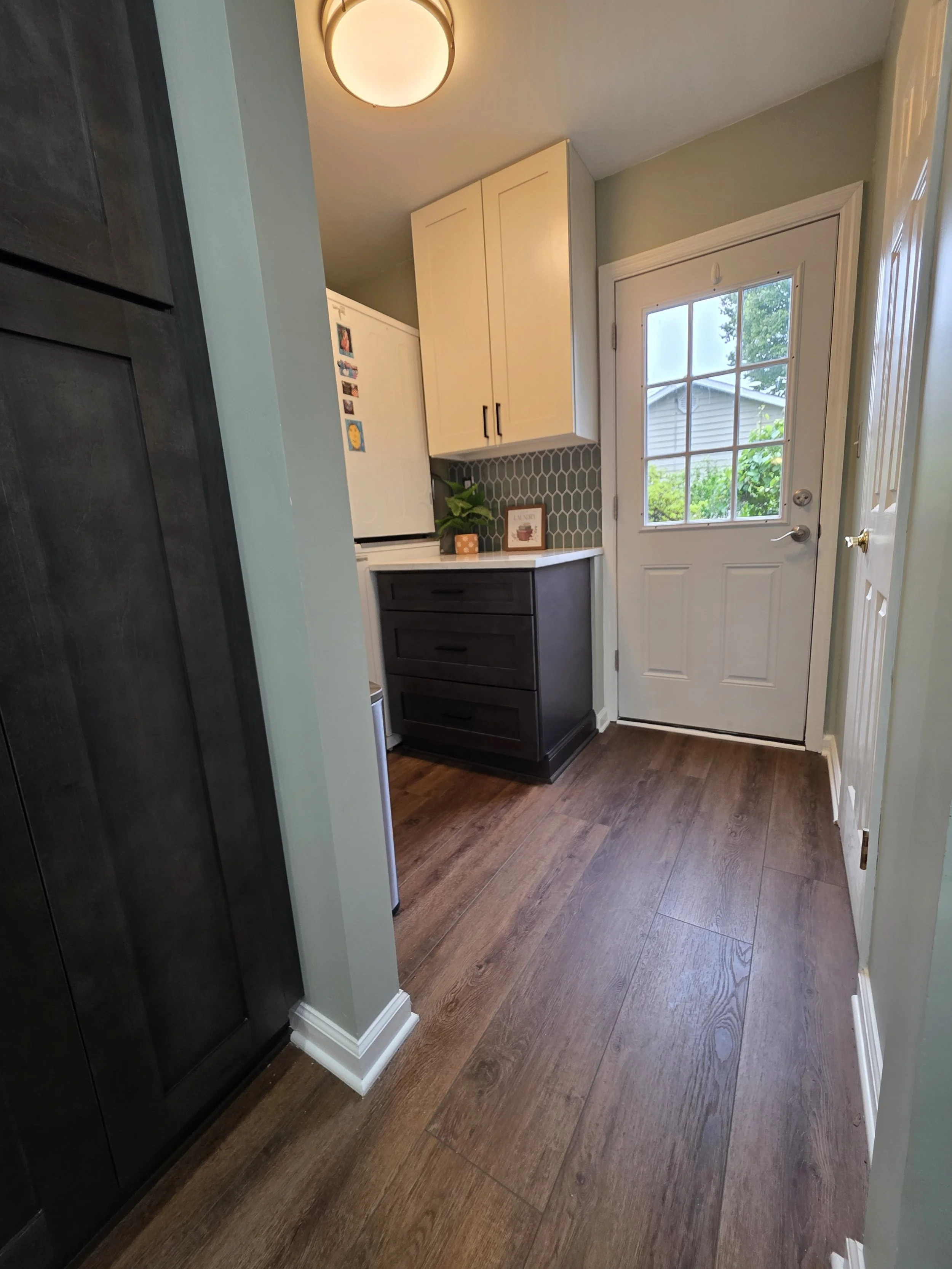 View through the refreshed laundry room toward the exterior door and new cabinetry.