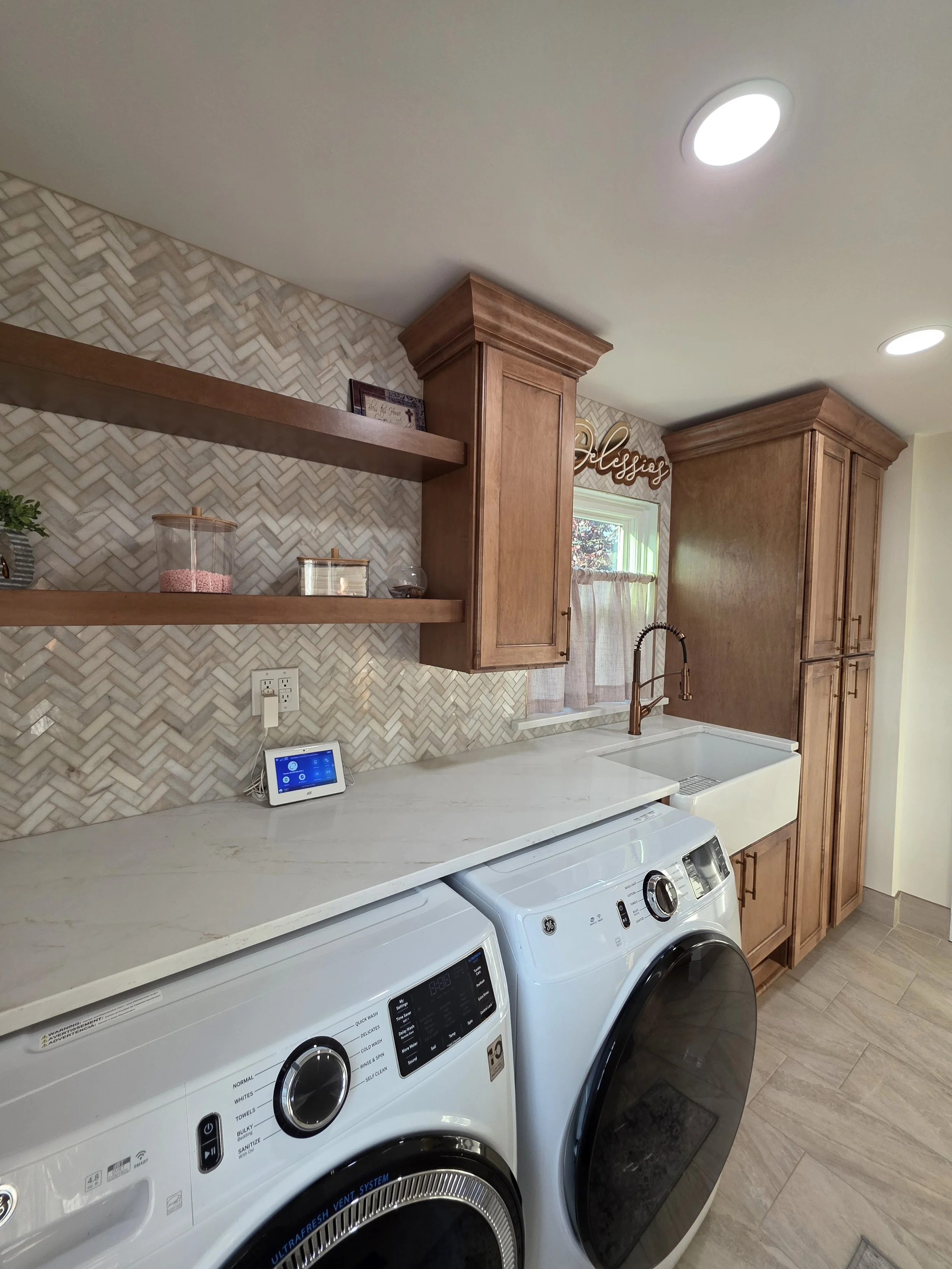 Wood shelving and patterned backsplash above the laundry countertop and appliances.