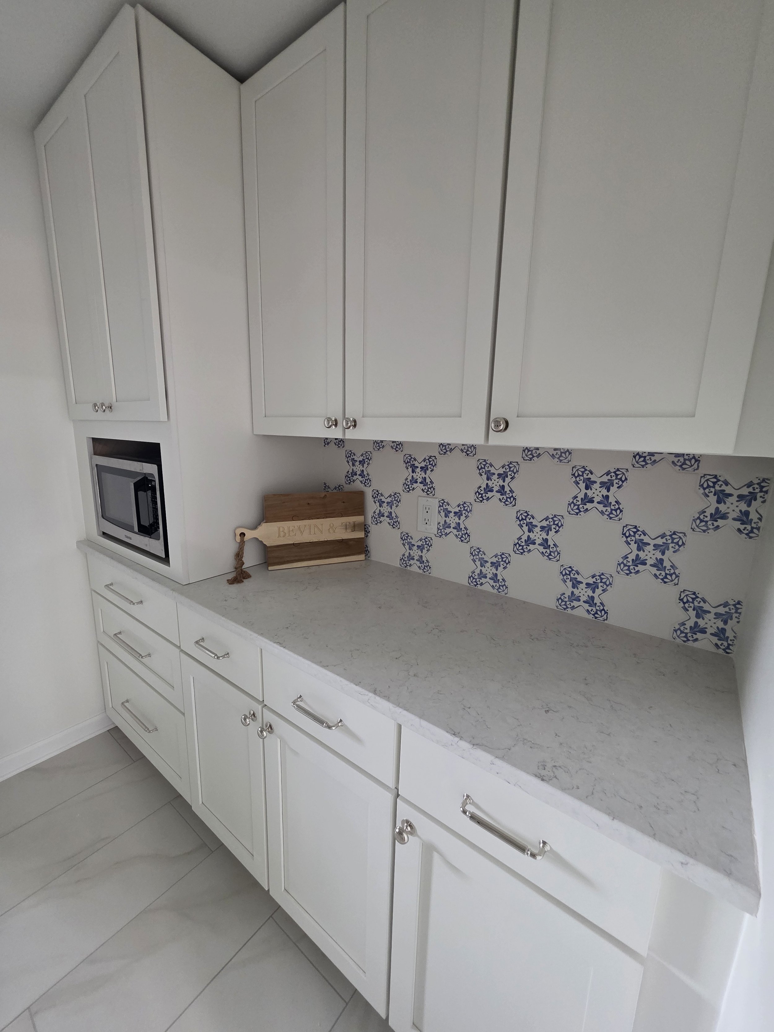 Pantry storage cabinets and light countertop with blue patterned tile.