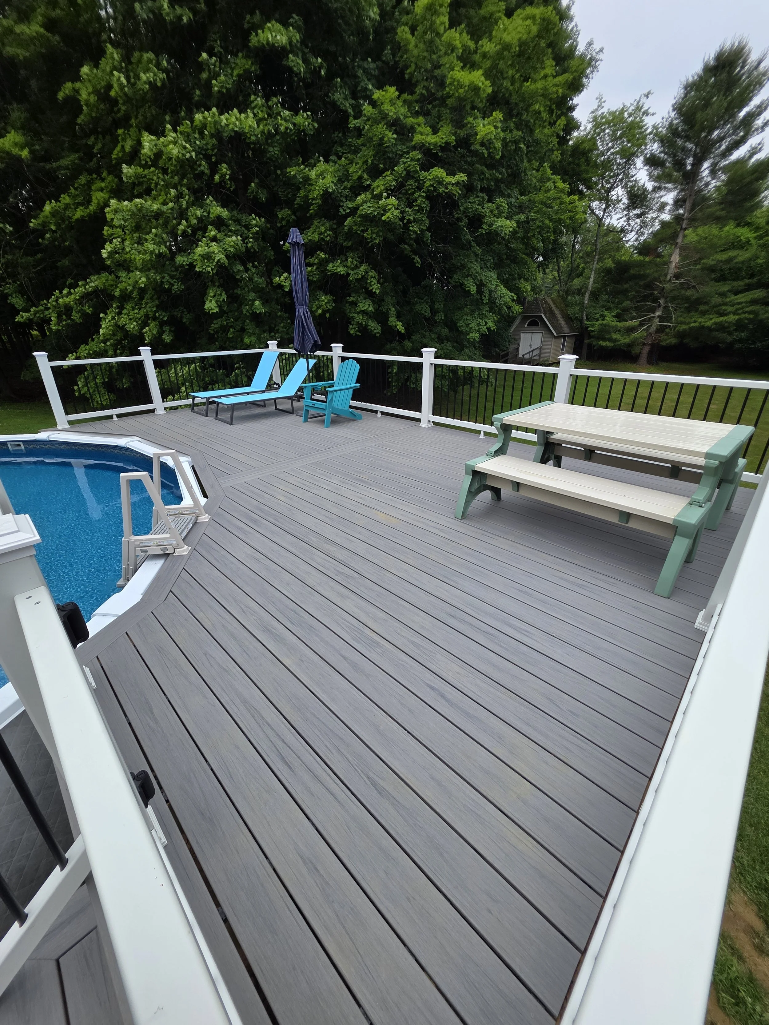 View across the new detached pool deck, showing gray decking and the railing beside the pool.