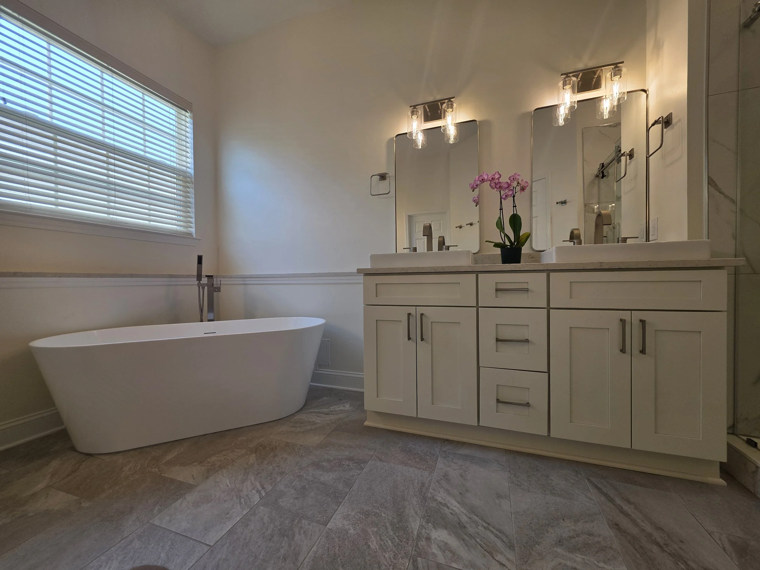 Freestanding tub beside the sink vanity and window.