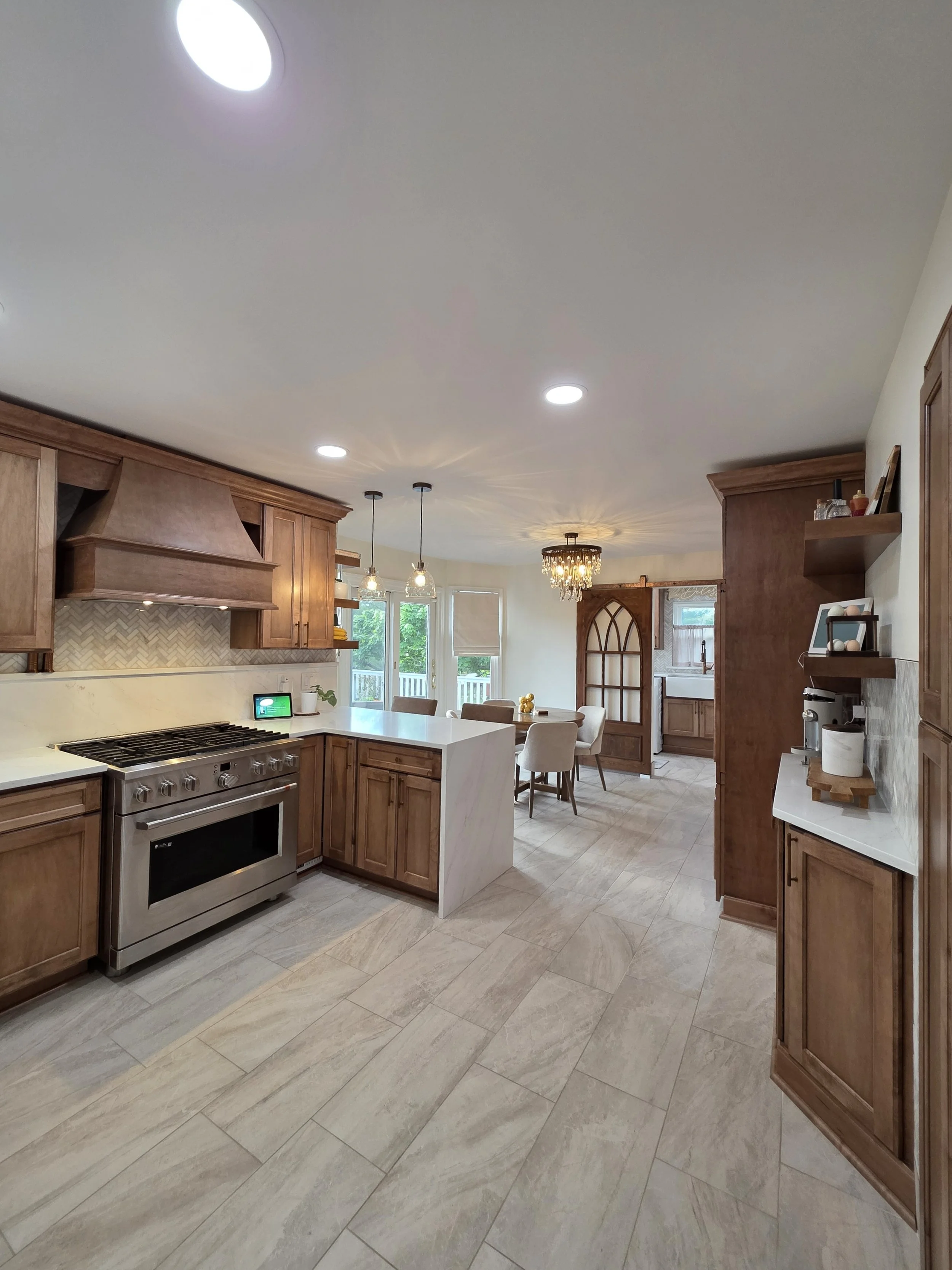 View through the kitchen toward the dining area with wood cabinetry and a stainless range.