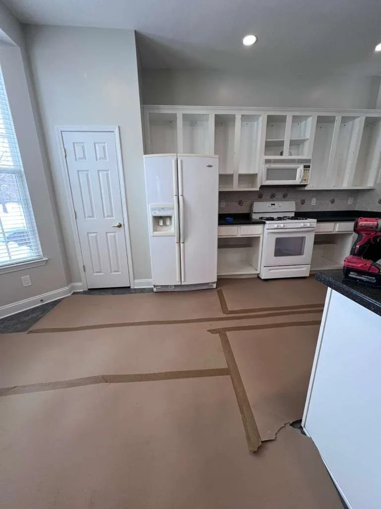Before renovation: the old refrigerator and range wall with white cabinetry.