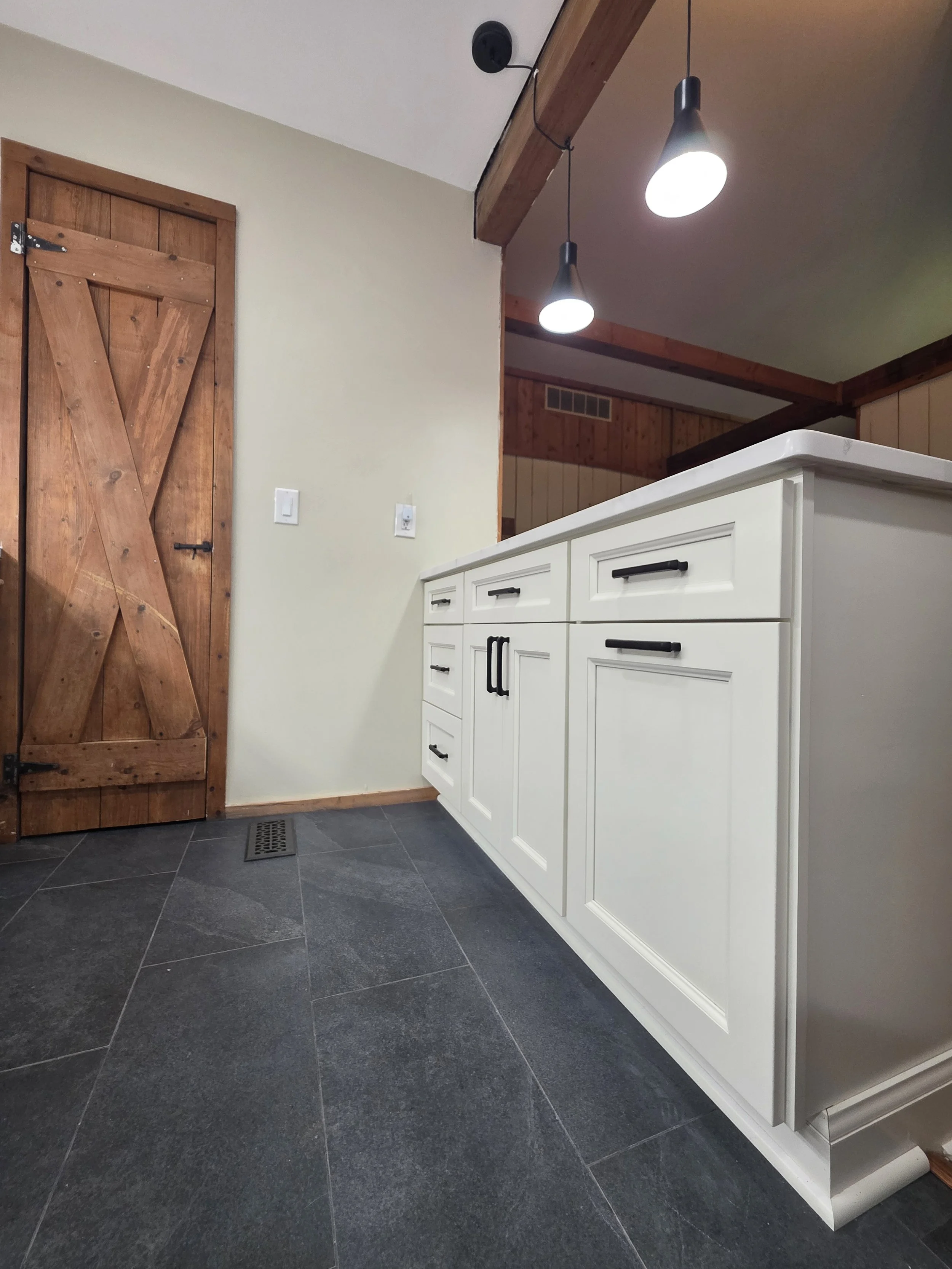 Peninsula drawers and dark tile flooring beside the wood door.