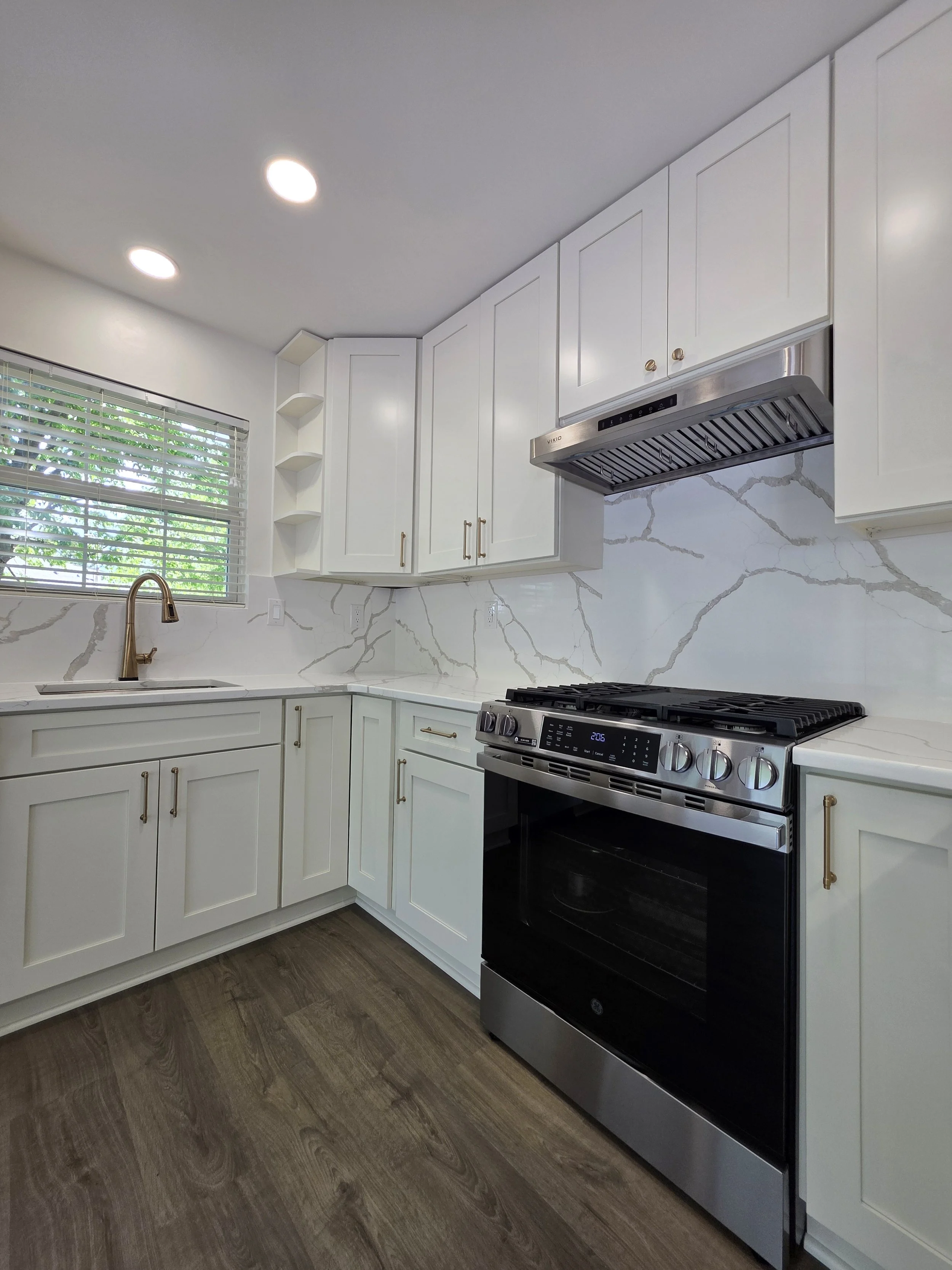 Close view of the range, sink corner and veined backsplash.