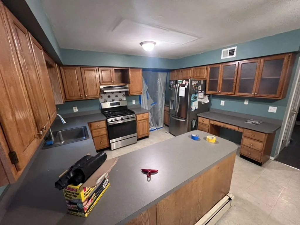 Kitchen before renovation with wood cabinets and older countertops.