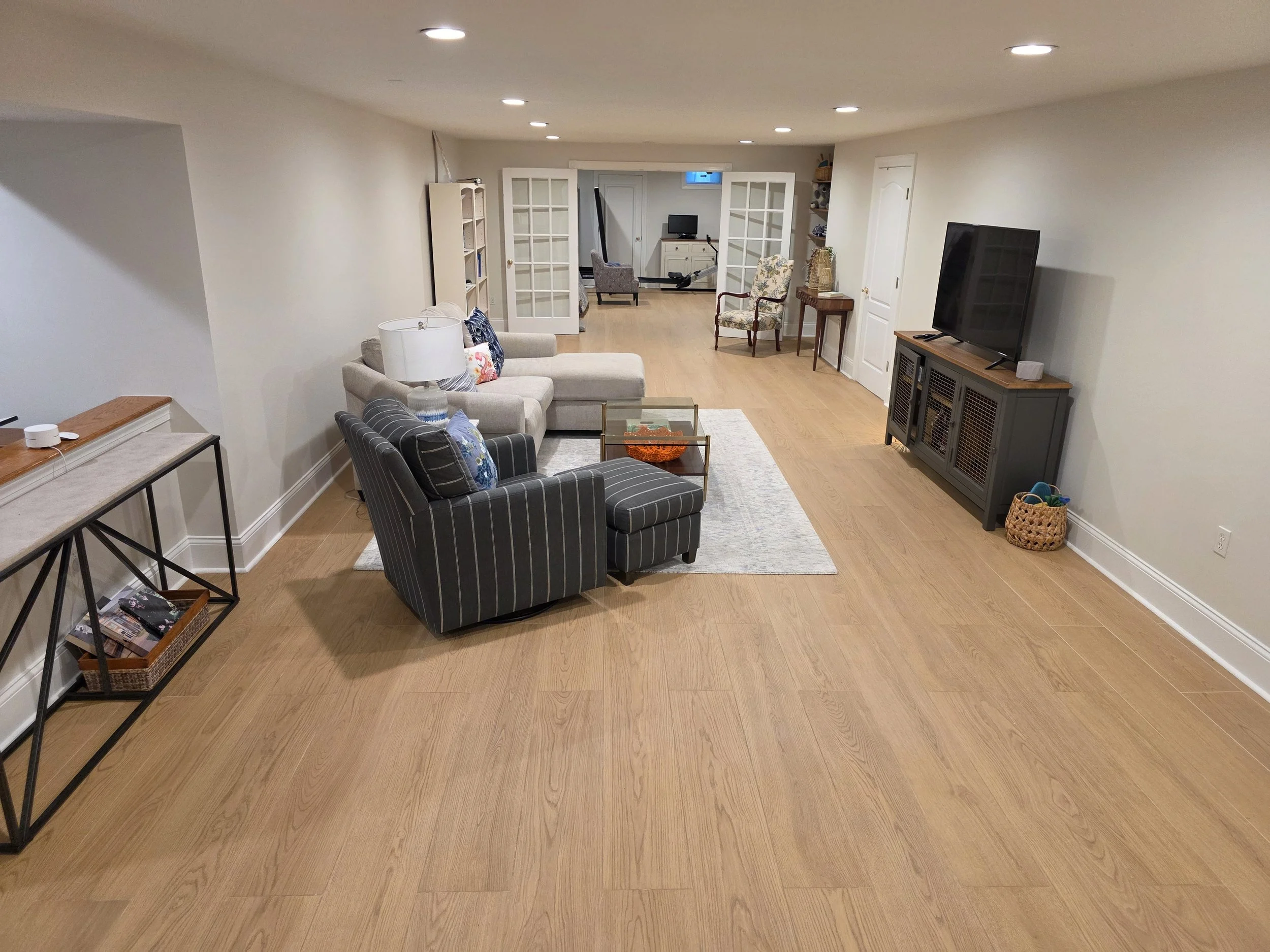 Wood-look tile throughout basement seating and recreation area.