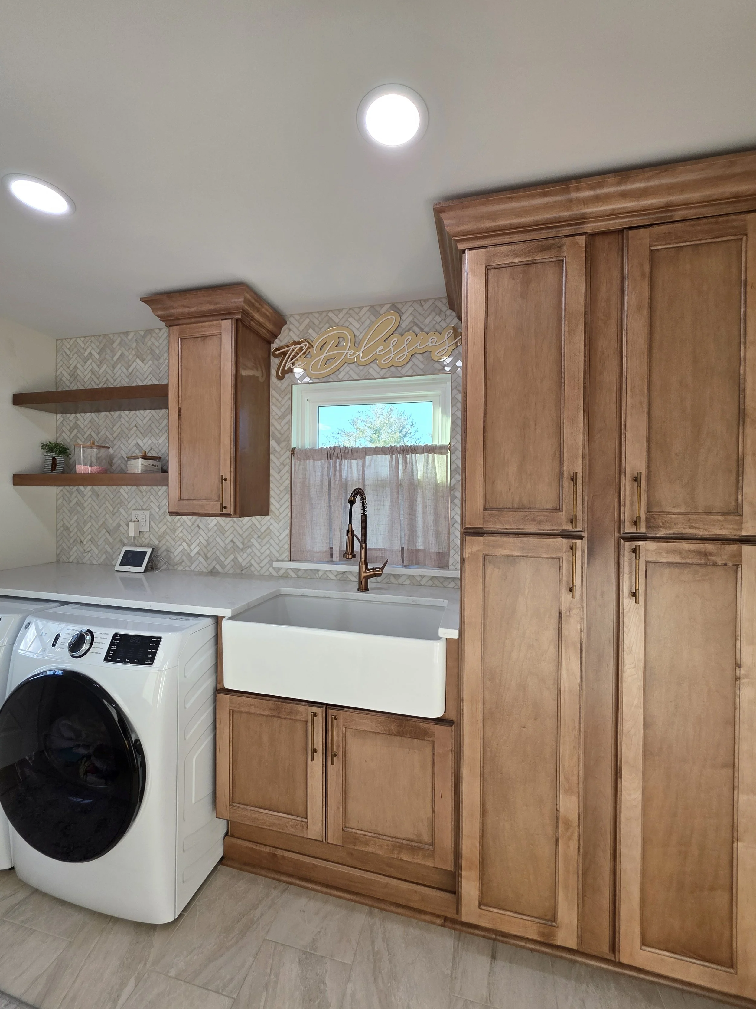Farmhouse sink beneath the window beside tall wood storage cabinetry.