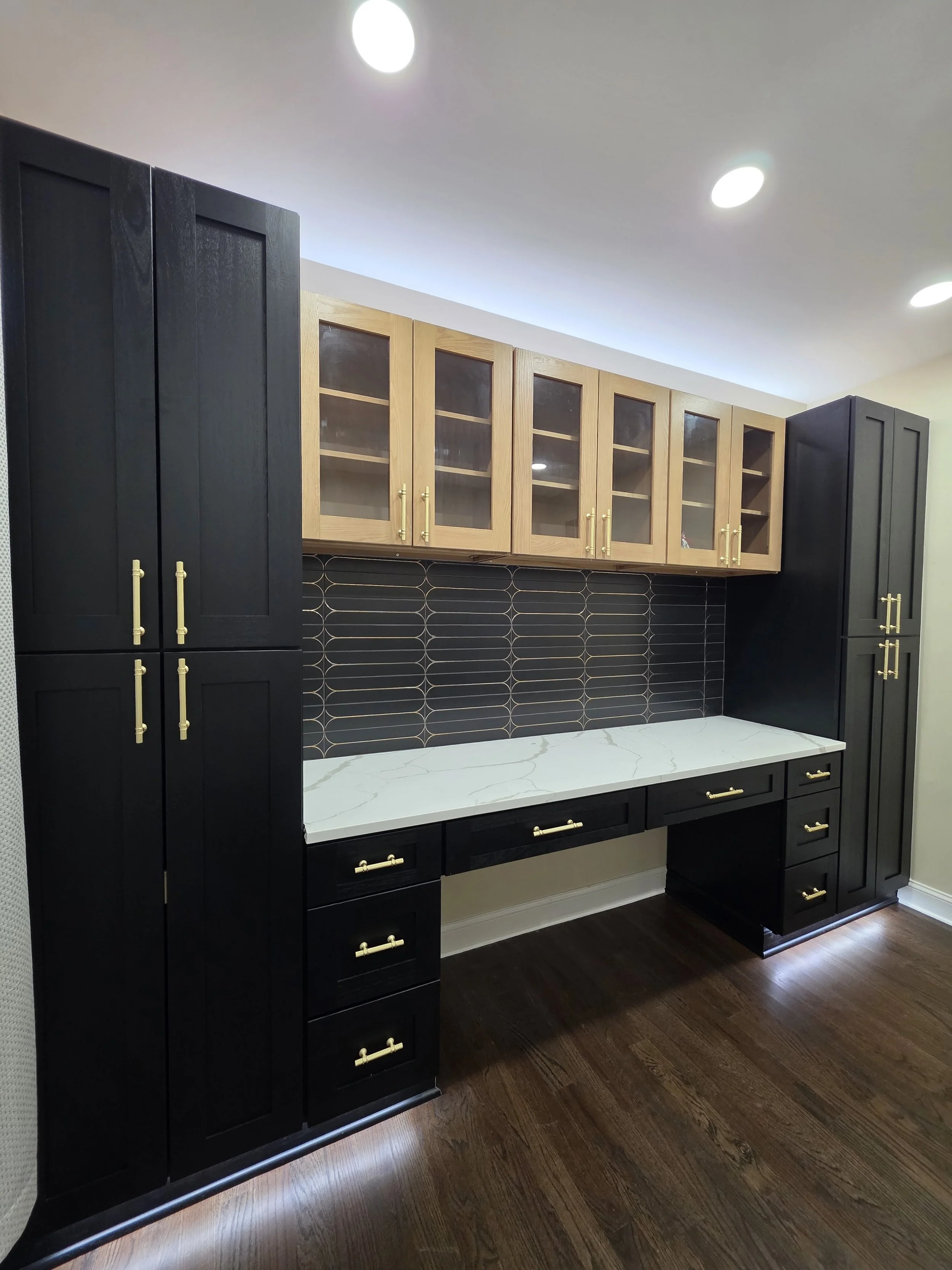Dark tall cabinets and wood upper cabinets with integrated lighting.