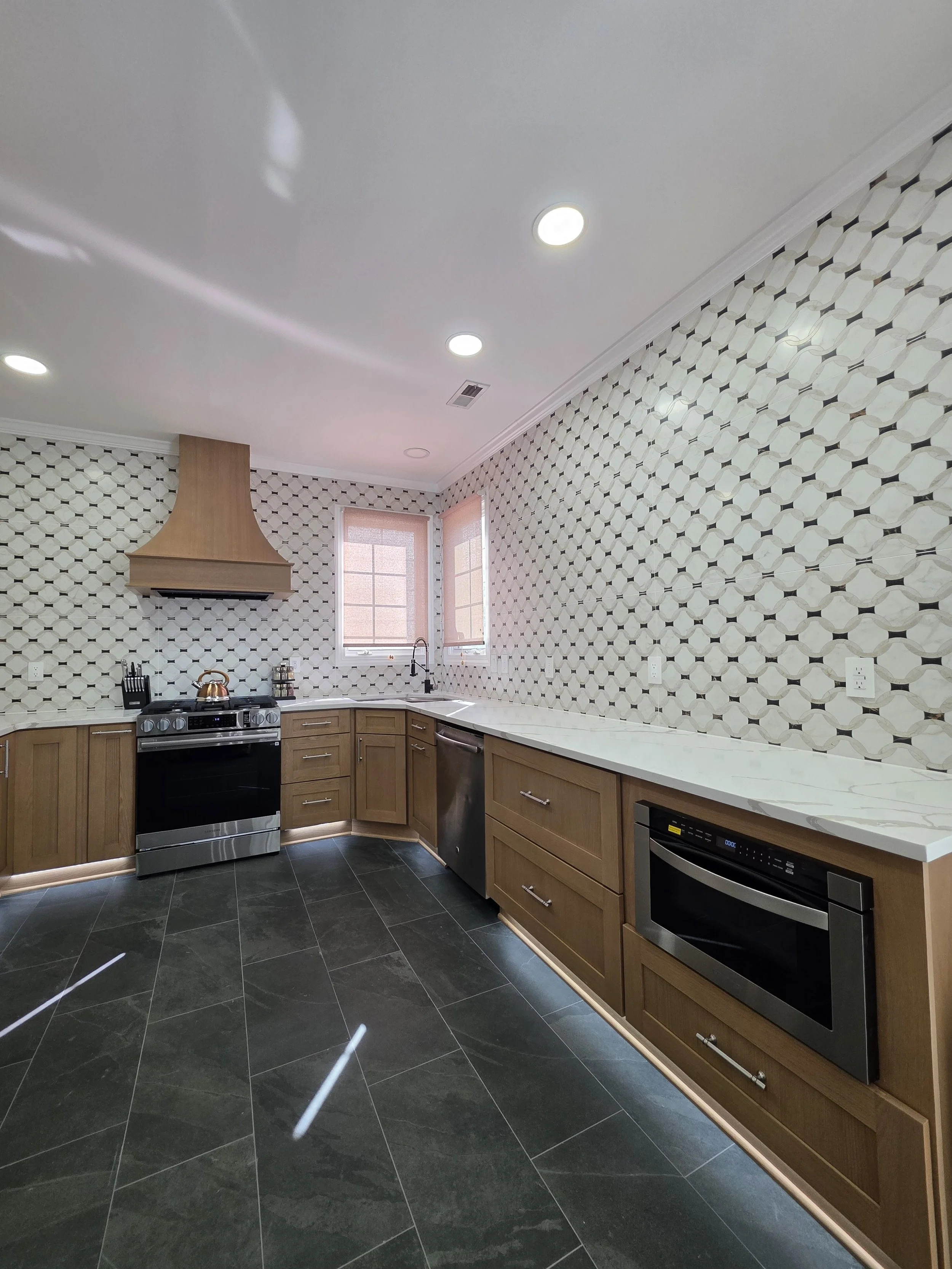 Kitchen view showing patterned tile walls and dark floor.