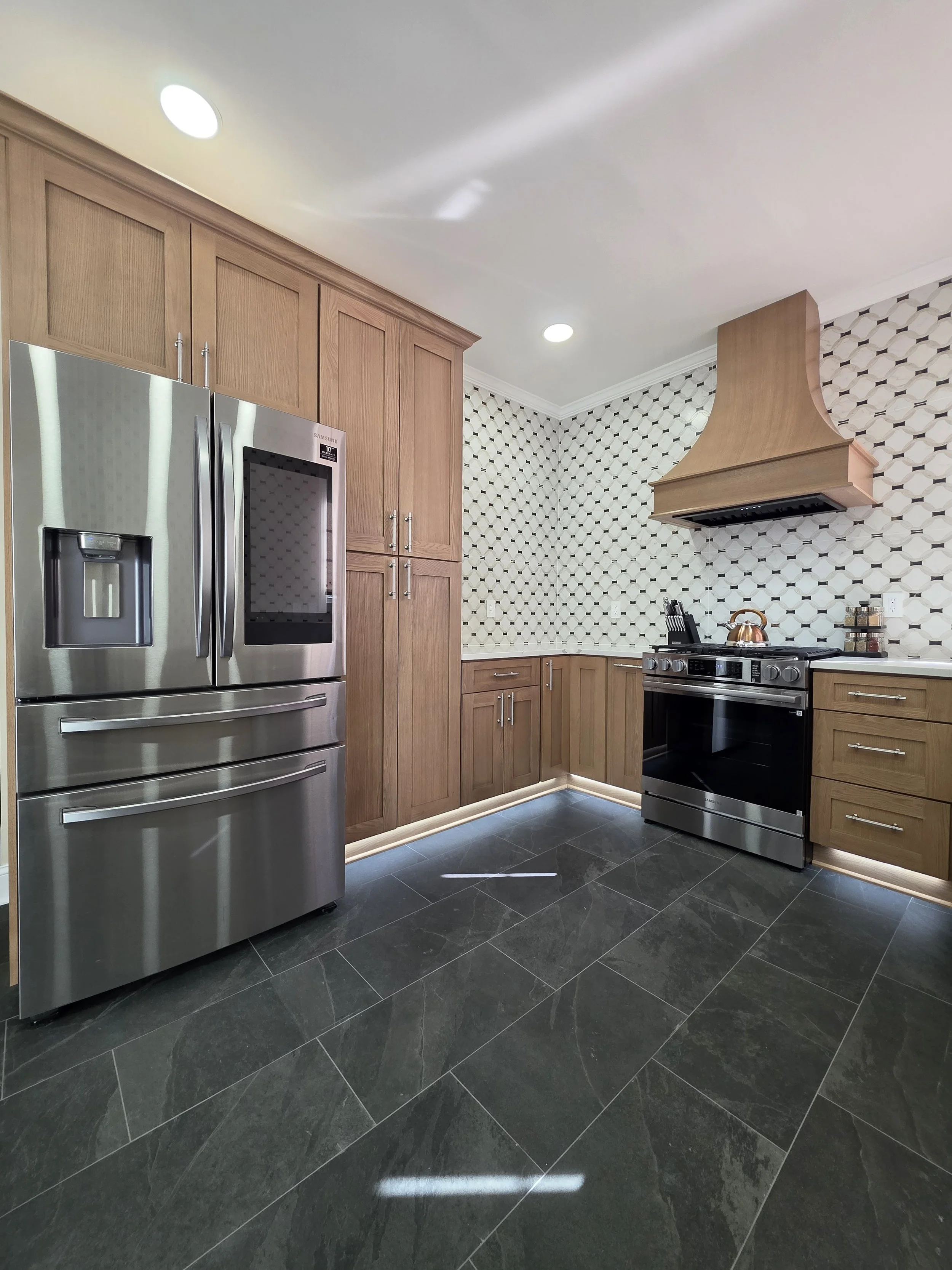 Wood cabinetry around stainless steel refrigerator and range.