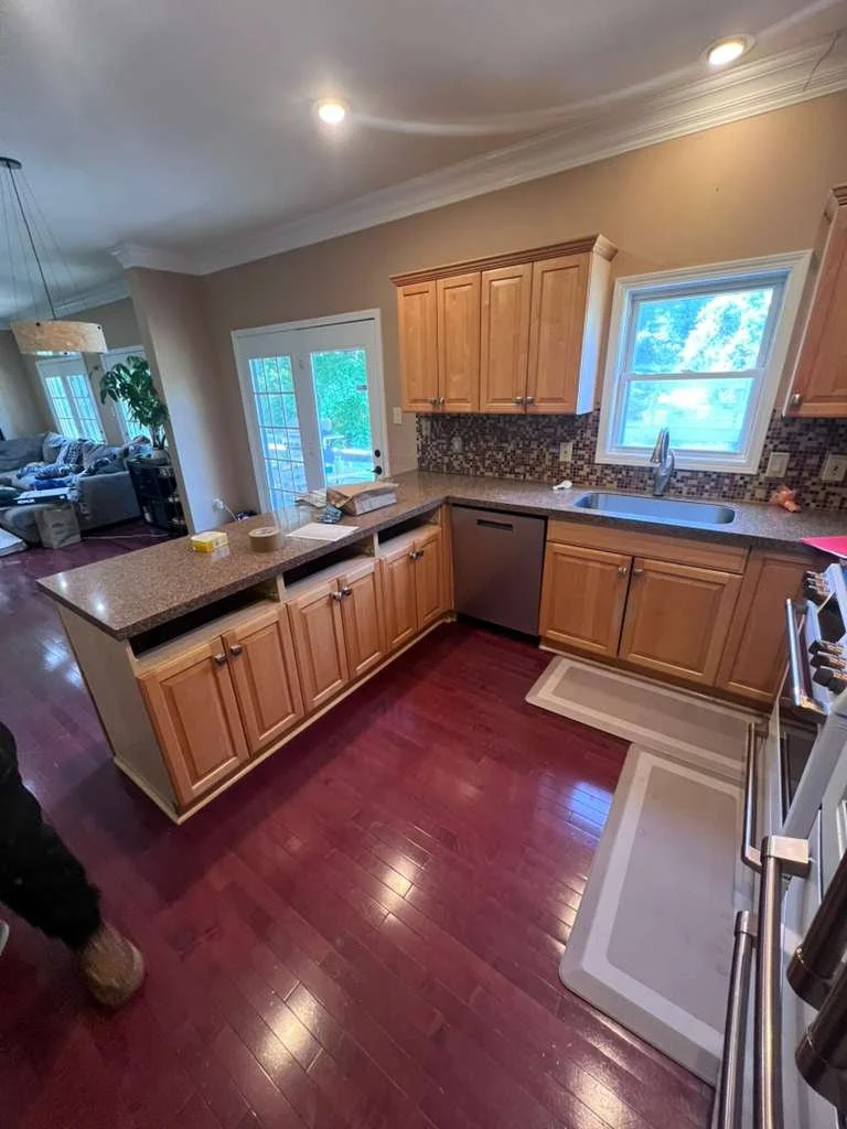 Before the kitchen update: wood-tone cabinets and dark countertops around the peninsula and sink.