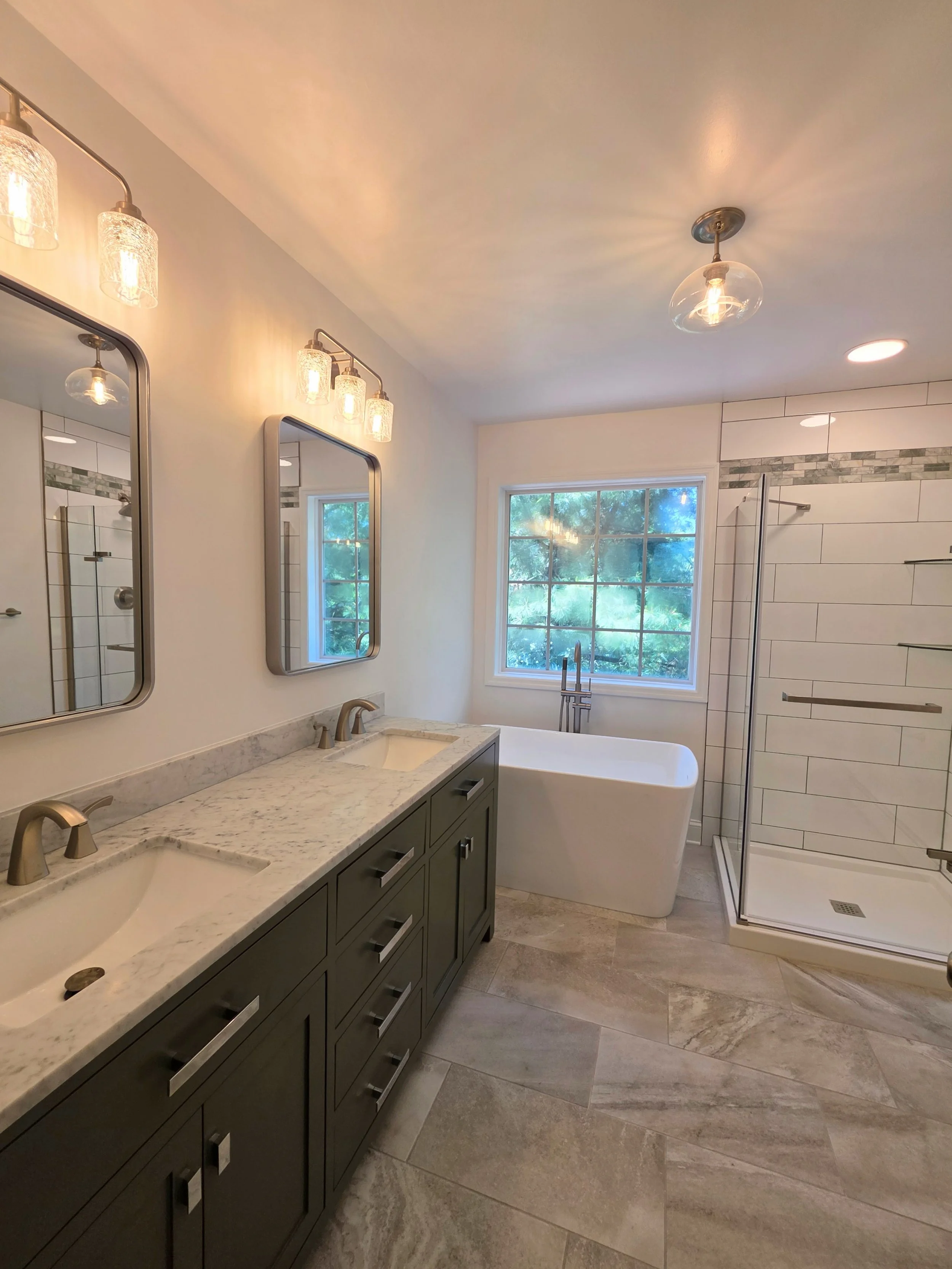 Wide view along the double vanity toward the freestanding tub and glass shower in Liz’s master bathroom.