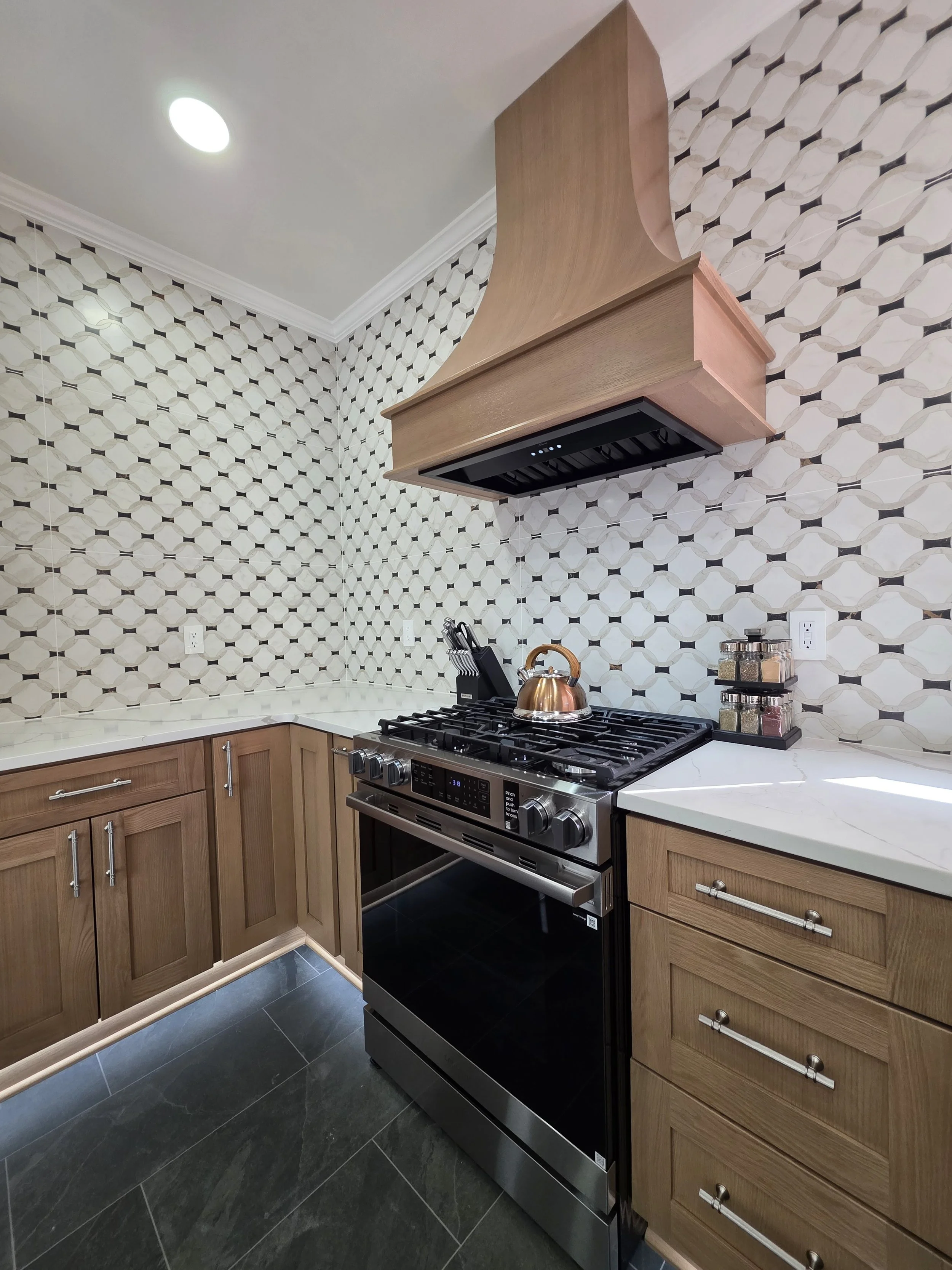 Range and wood hood against patterned backsplash.